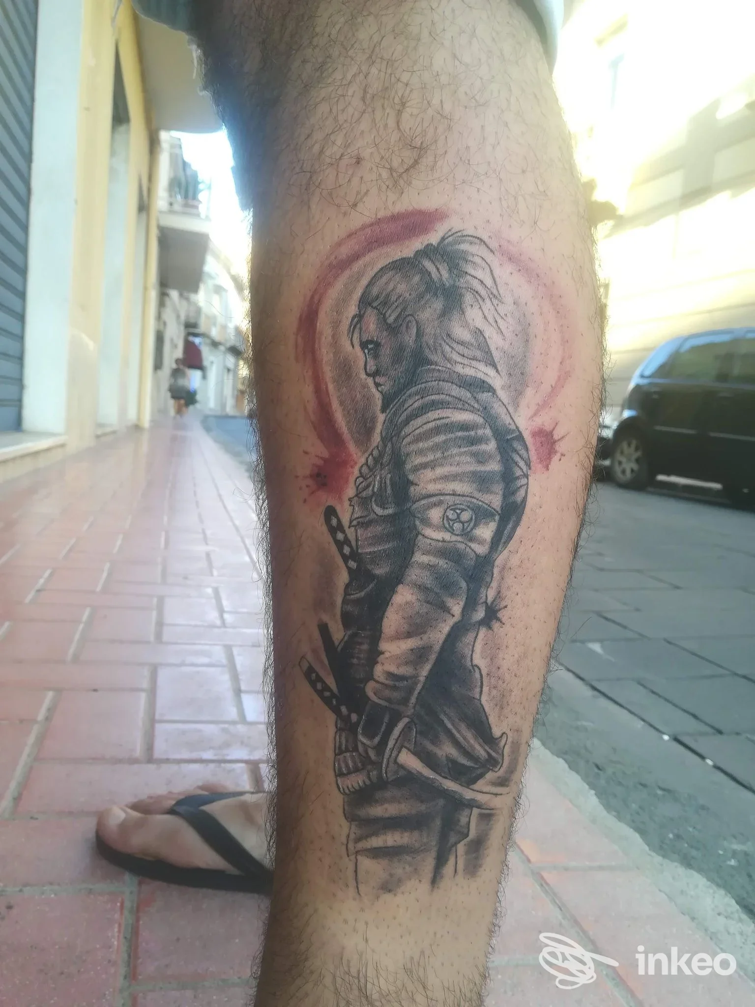 Tattoo realistico su gamba di persona, raffigurante un guerriero con spada, visibile nitidamente sulla pelle.