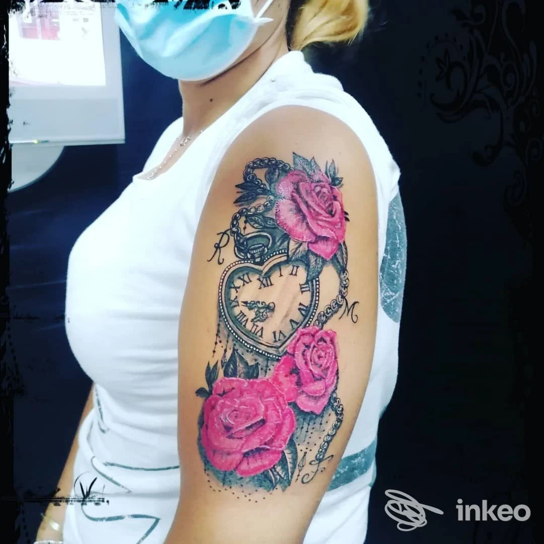 Tatuaggio su braccio di una persona con rose rosa e orologio, realizzato sulla pelle, visibile in una foto pubblica.