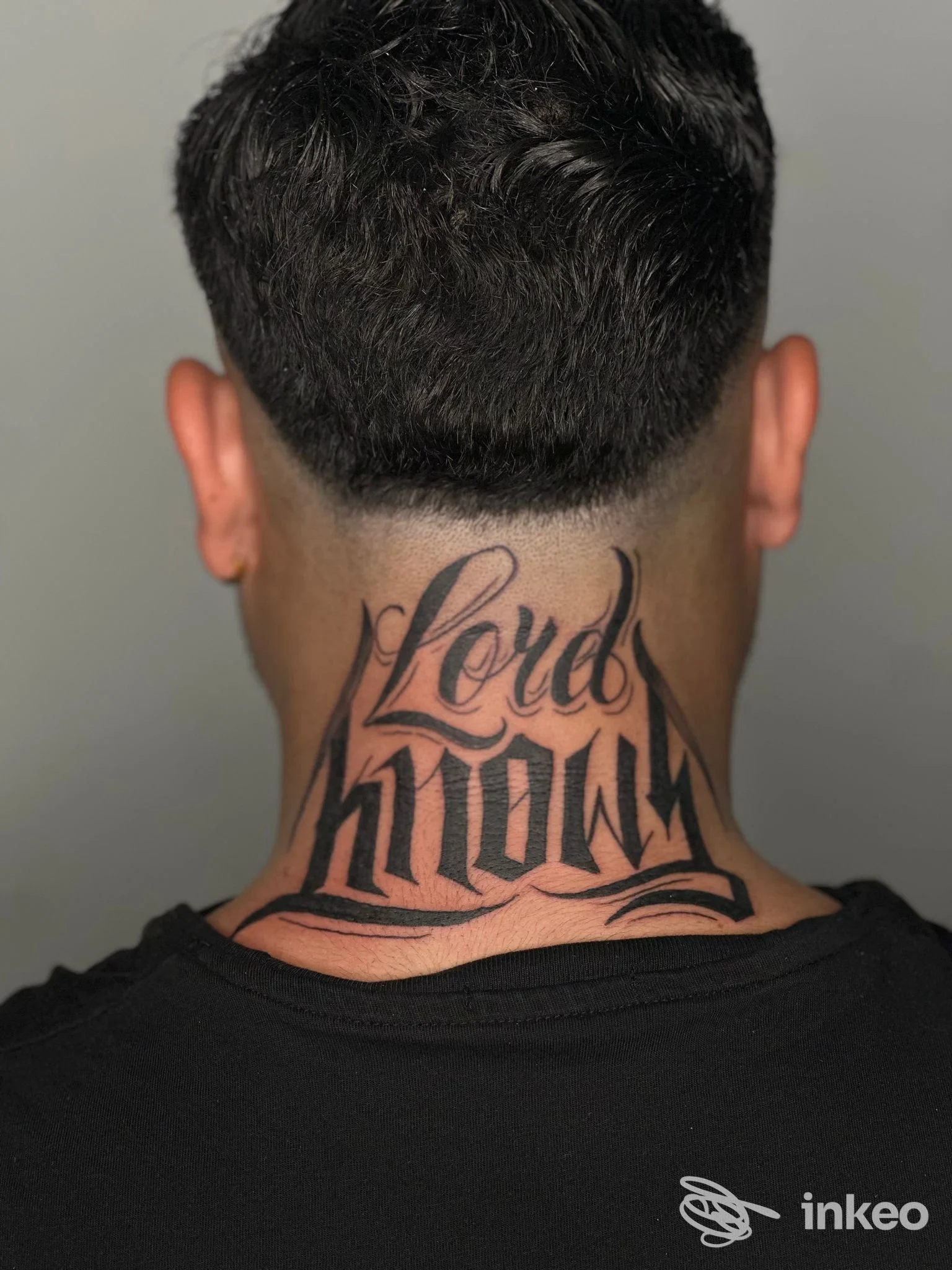 Tattoo sul retro del collo di una persona, lettering stilizzato in nero, nessun volto visibile, foto focusing sul tattoo, studio Aviink di San Marco Evangelista.