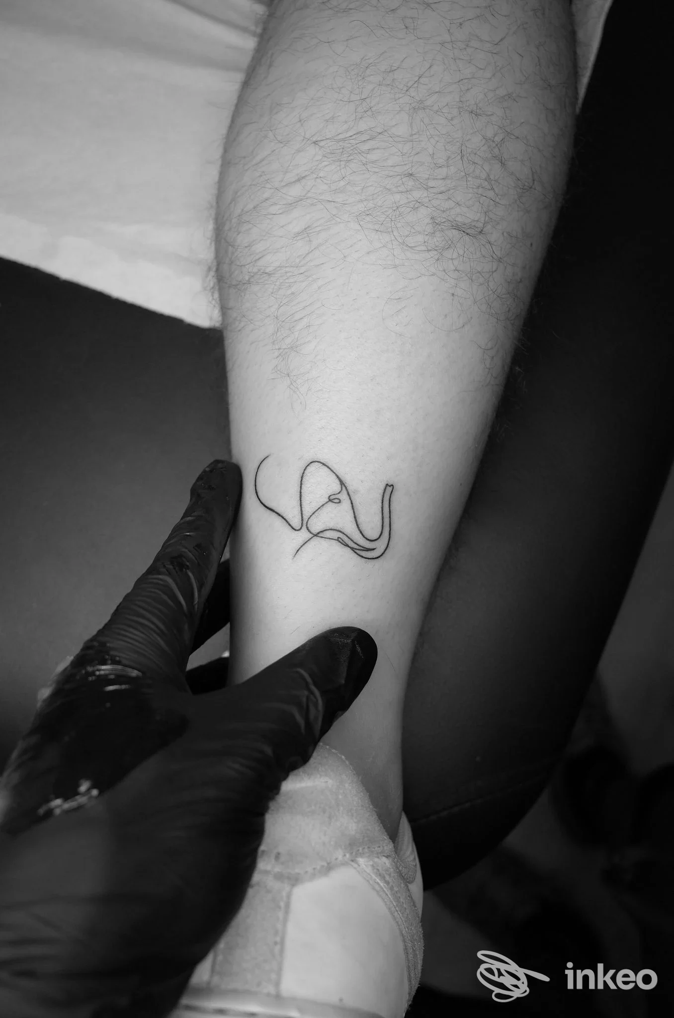 Tatuaggio lineare sul polso di una persona, visibile solo l’avambraccio; nessun volto intero, luce sufficiente e sfondo scuro; studio Mike Biscuit a Parete non è visibile nel frame.