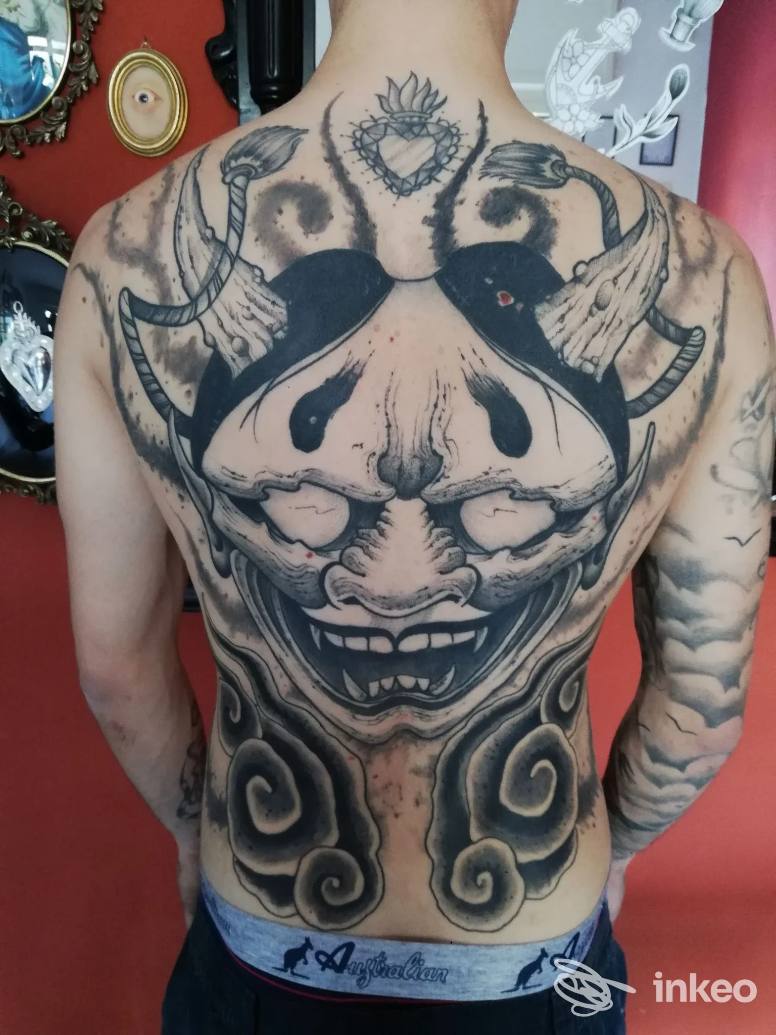 Schiena intera visibile con tatuaggio realistico a tema clown demoniaco, con motivi neri e sfumature grigie su tutto il dorso, da mercatino San Severino.