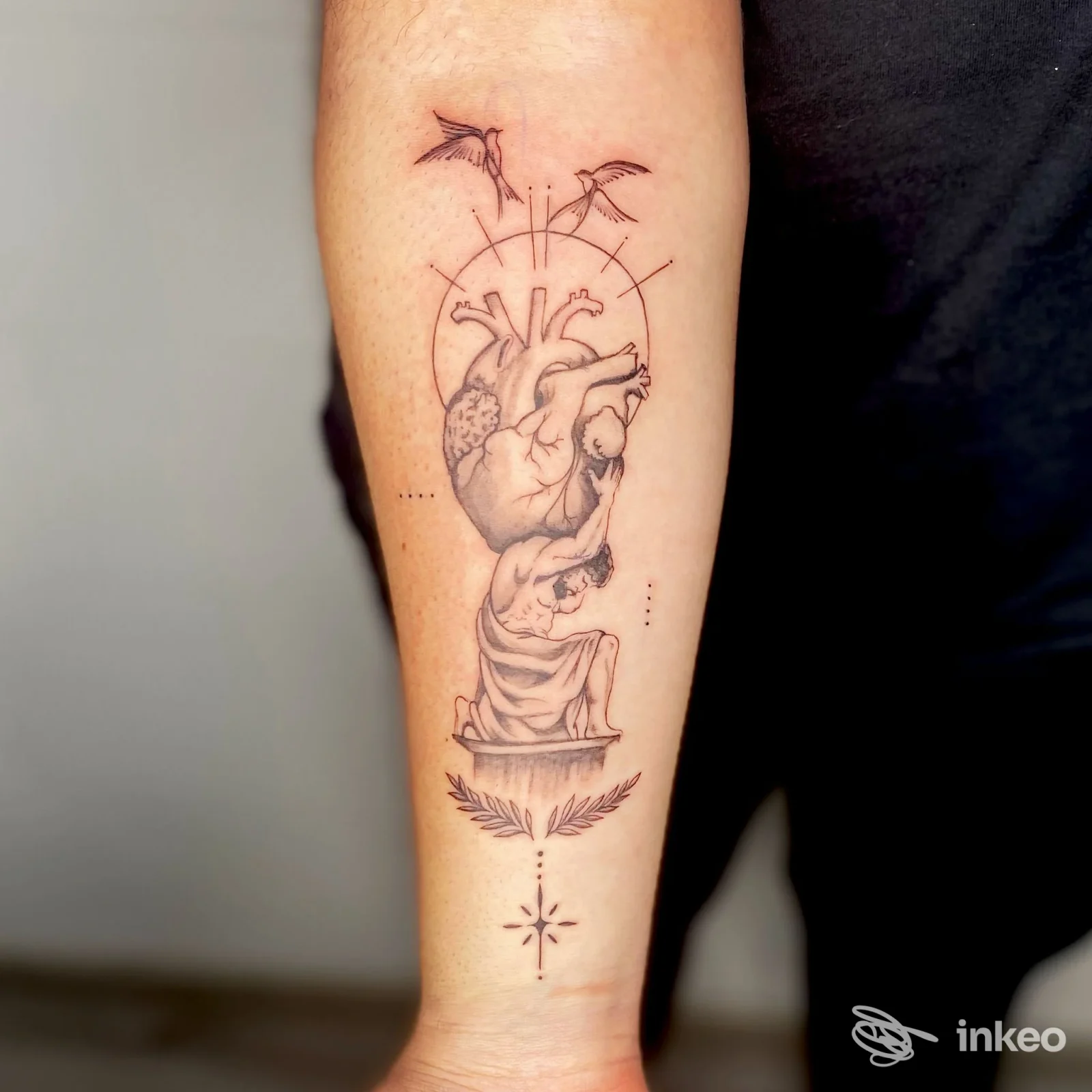 Tattoo sul braccio raffigurante un cuore anatomico con elementi decorativi, linee nere su pelle chiara, senza volto visibile.