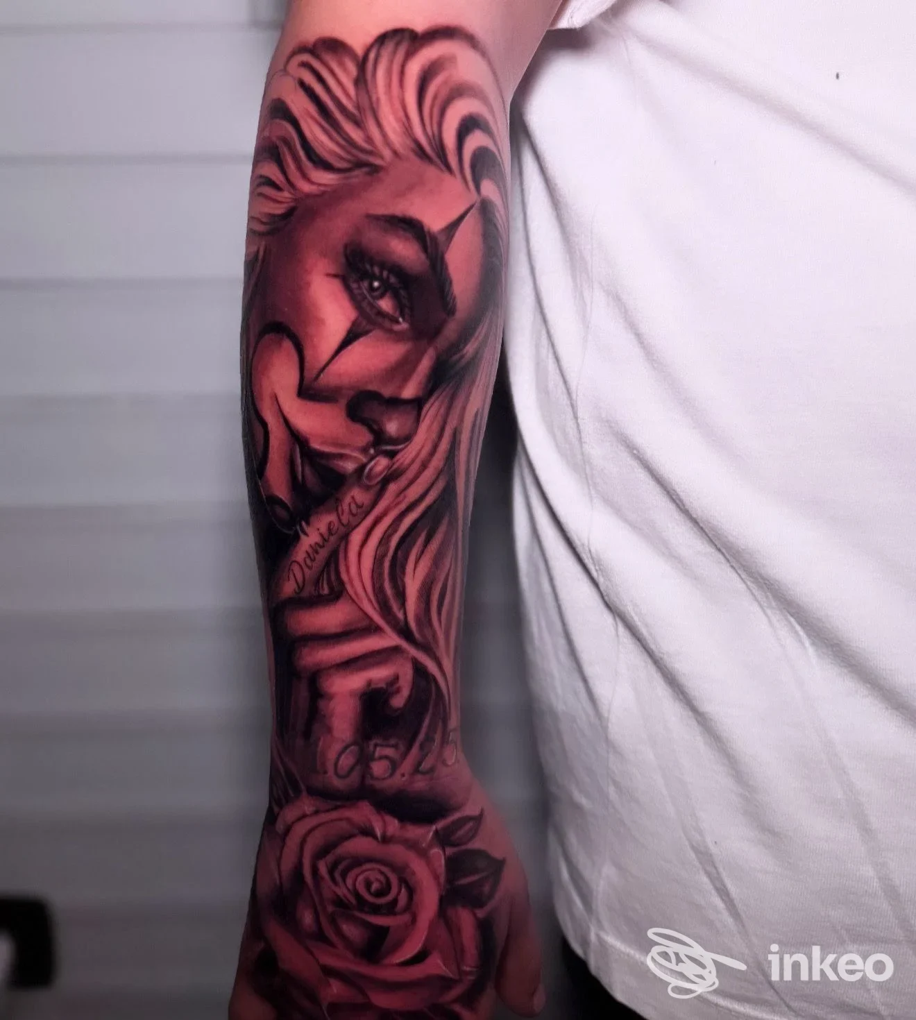 Tattoo realistico in bianco e nero sull'avambraccio raffigurante un volto femminile e una rosa, eseguito su pelle reale.