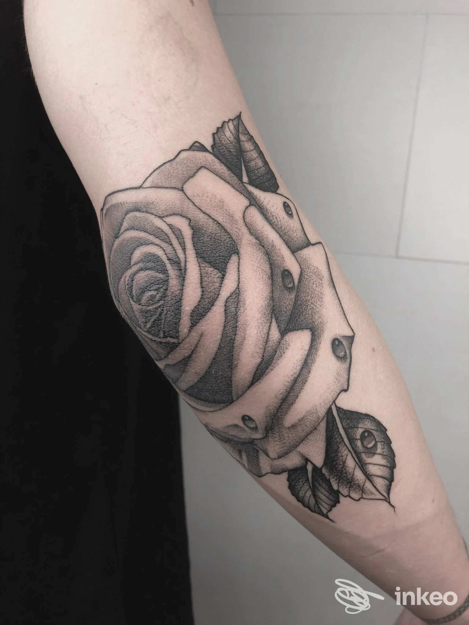 Tatuaggio realistico di rosa su avambraccio realizzato da Play Tattoo a Napoli, in tonalità nero-grigio, con dettagli di foglie e nervature.