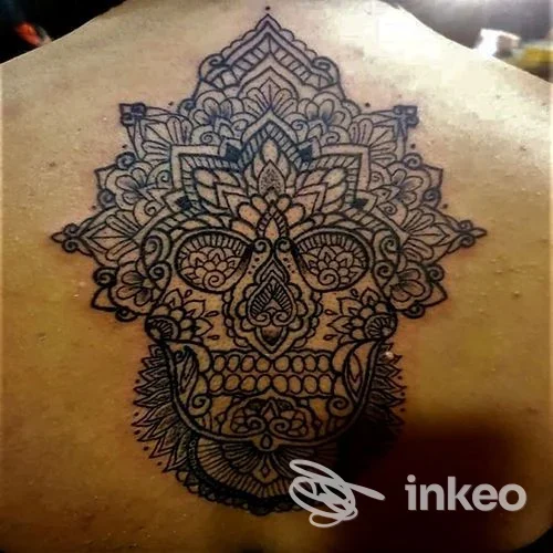 Tattoo stilizzato in stile sugar skull sul dorso, disegno inciso con linee nere e motivi floreali complessi.
