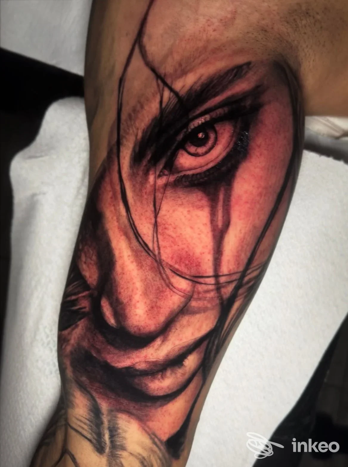 Particolare di un tatuaggio realistico su pelle che ritrae un volto con occhio intenso, tratti scuri e linee ad anelli, realizzato presso Old Owl's Skull Tattoo a Casoria.