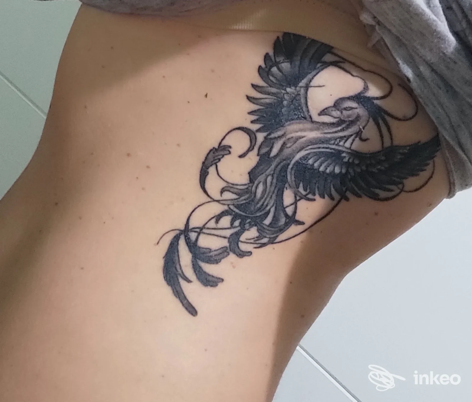 Tattoo in bianco e nero di un uccello stilizzato a ali spiegate sul fianco di una persona, eseguito nello studio Prince Tattoo a Quadrivio.