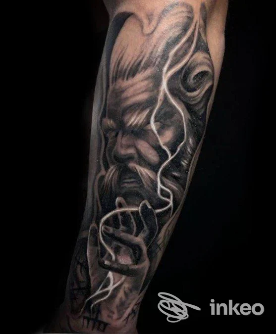 Tattoo realistico in bianco e nero su braccio, raffigurante un volto intenso accompagnato da mani e linee decorative, nello stile raffigurato.
