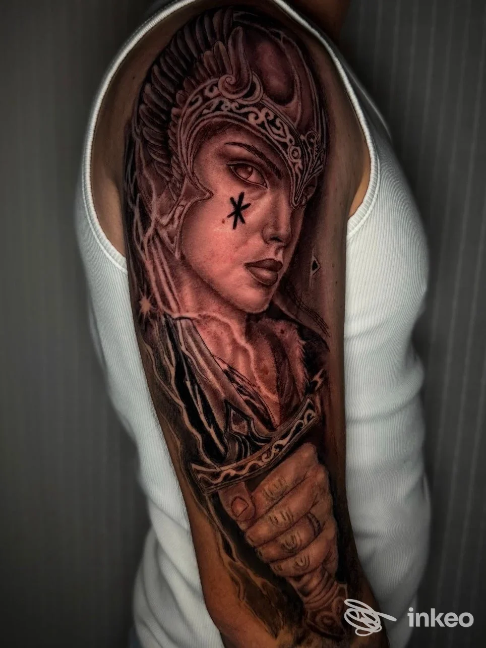Tattoo a braccio raffigurante una figura femminile con copricapo, realizzata sulla pelle di una persona, tonalità scure e dettagli raffinati.