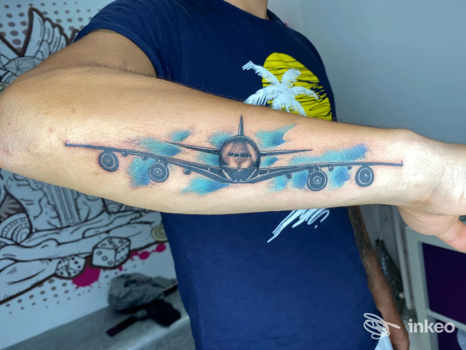 Tattoo sul braccio raffigurante un aereo con fusoliera centrale, sfondo blu chiaro, eseguito presso Christattoo a Salerno.