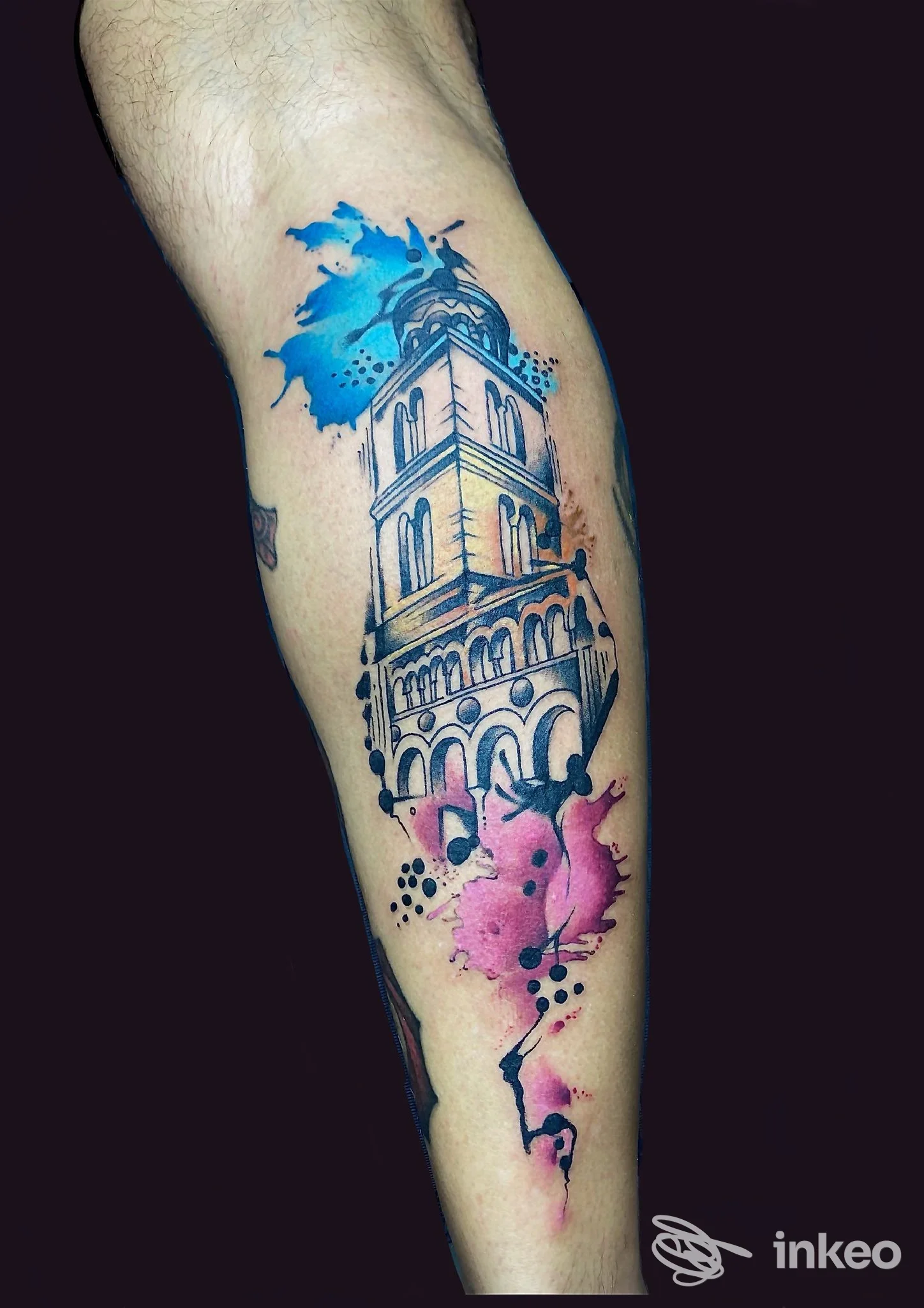 Tattoo colorato su avambraccio: architettura in stile acquerello con schizzi blu e rosa su pelle.