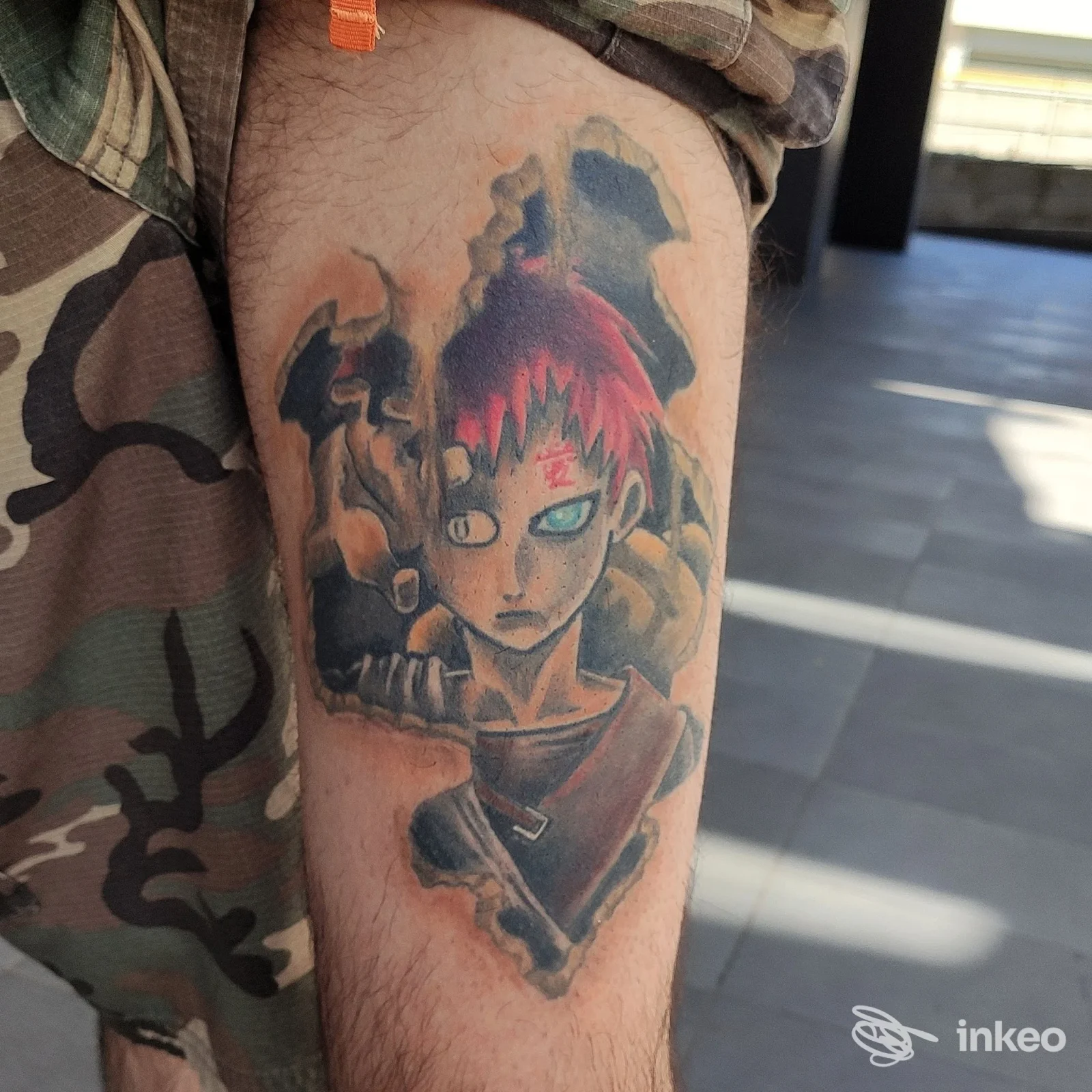 Tatuaggio colorato su polpaccio raffigurante un personaggio manga/animazione, con colore rosso sui capelli e toni scuri lungo il corpo, visibile su pelle reale presso uno studio Ink Tales Tattoo a Baronissi.