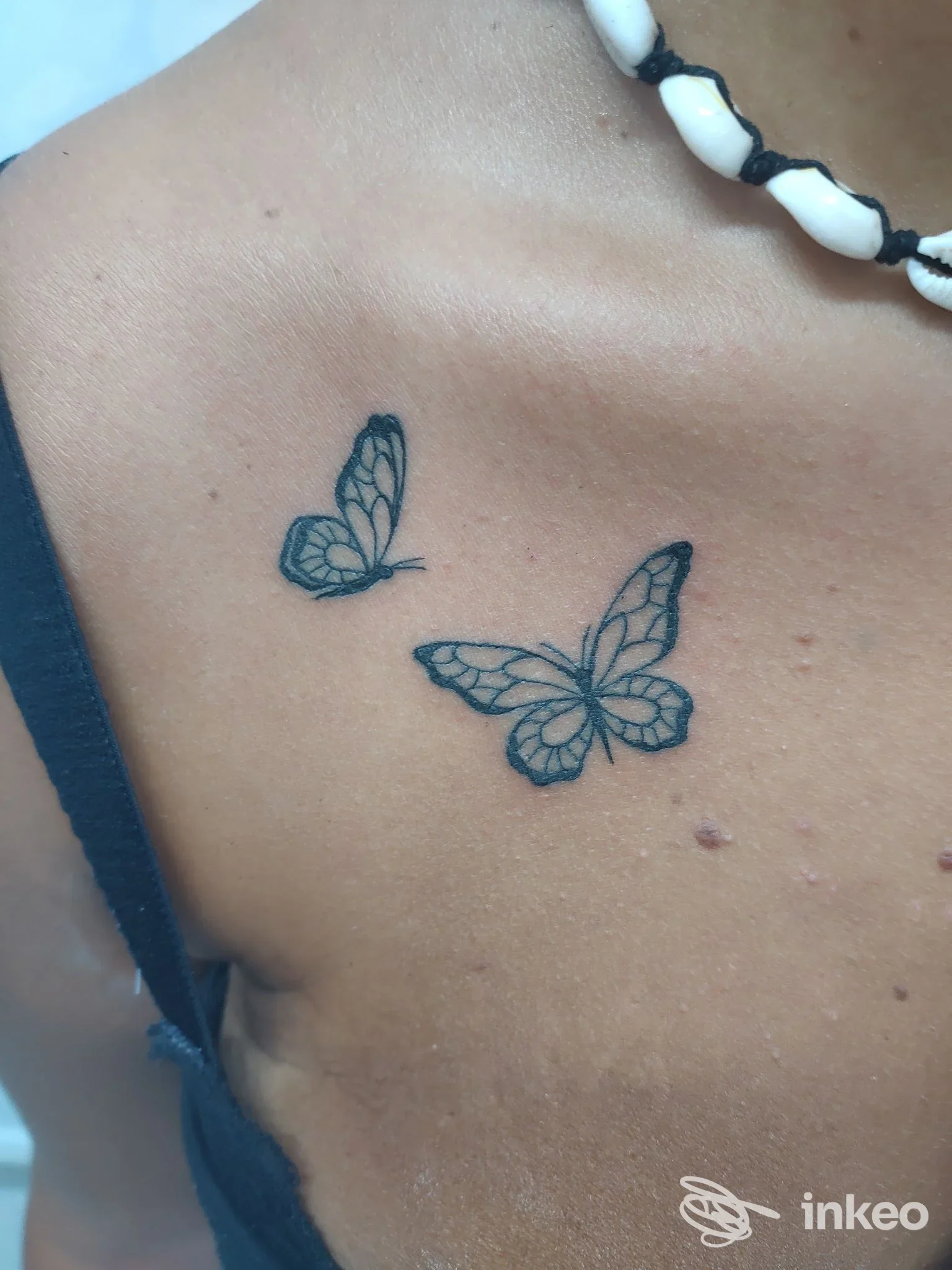 Due tatuaggi farfalla in stile linework, realizzati sulla pelle della spalla/torace, senza volto visibile e senza elementi di overlay sociale; studio Luka’s Tattoo Piercing a Napoli.