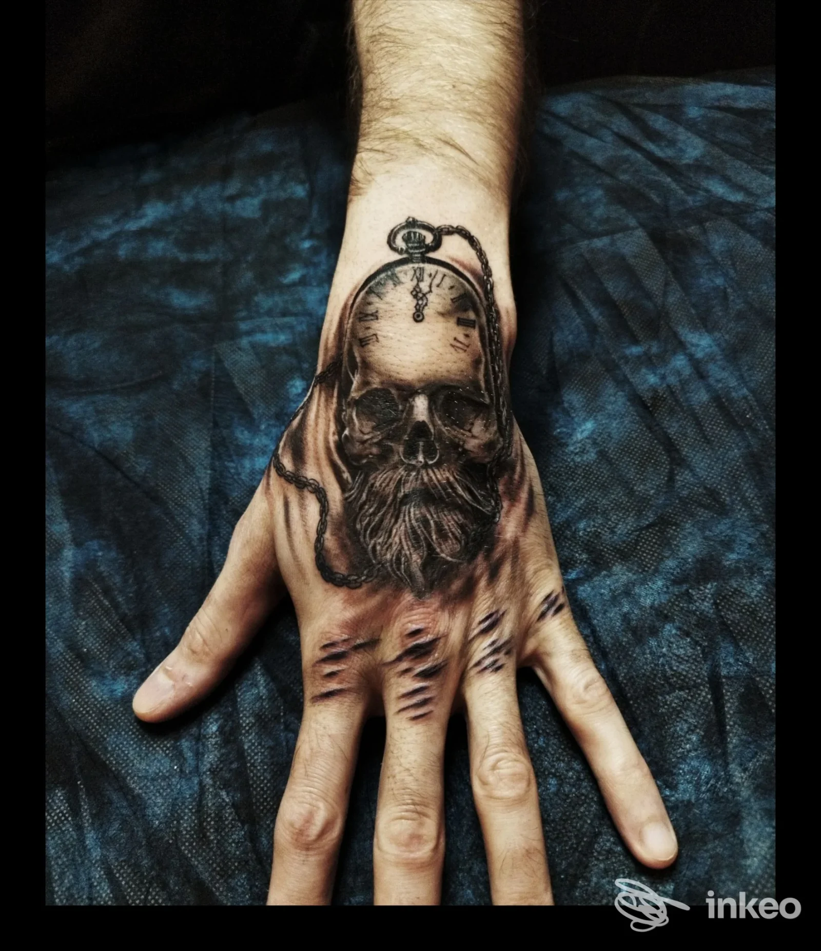 Tatuaggio realistico sul dorso della mano, raffigurante un volto scheletrico con dettagli che imitano luci e ombre sulla pelle.