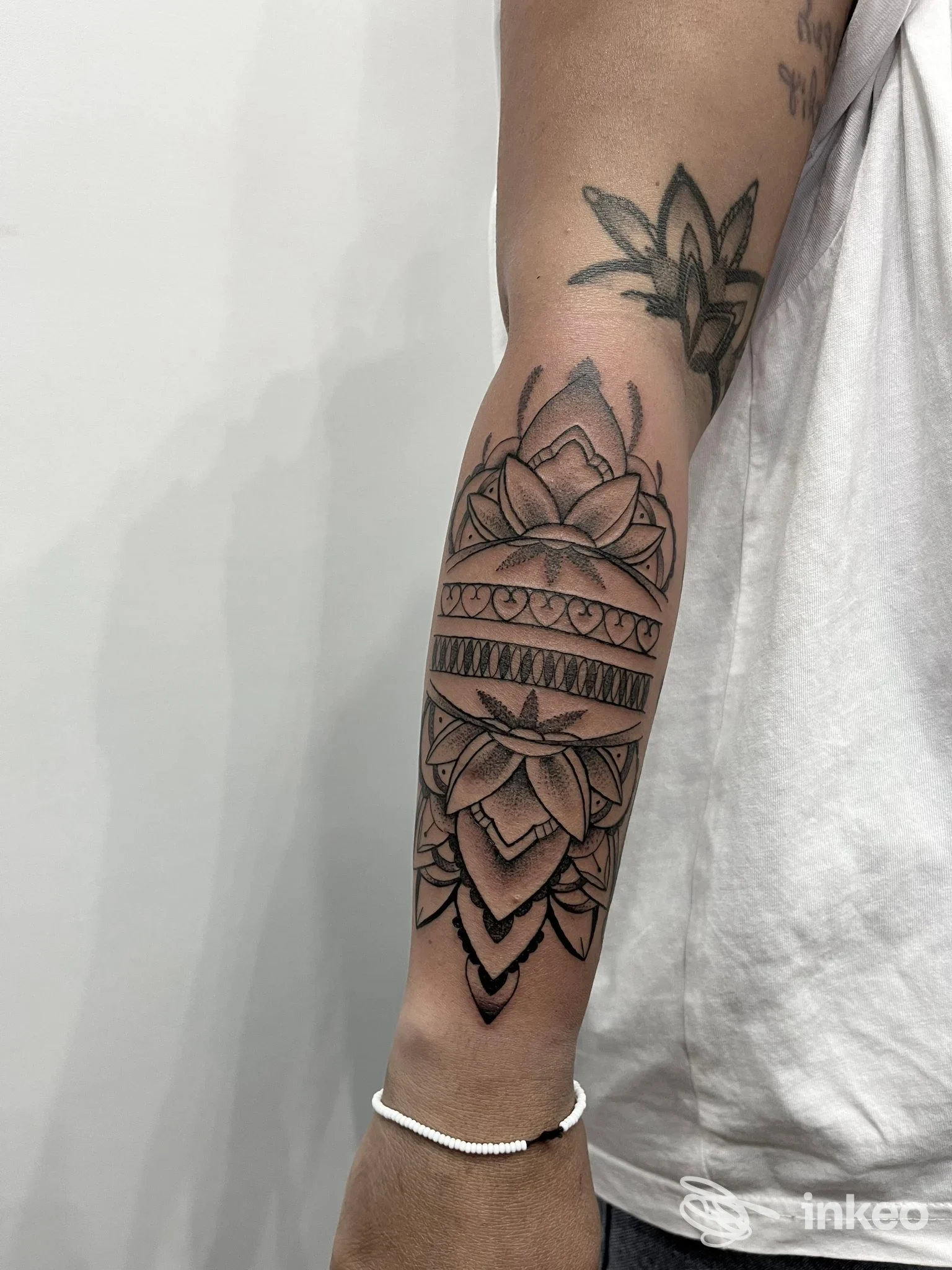Braccio con tatto geometrico a mandala e loto, tatto recente su pelle chiara, vista laterale, in primo piano; studio Drop Tattoo, Napoli.