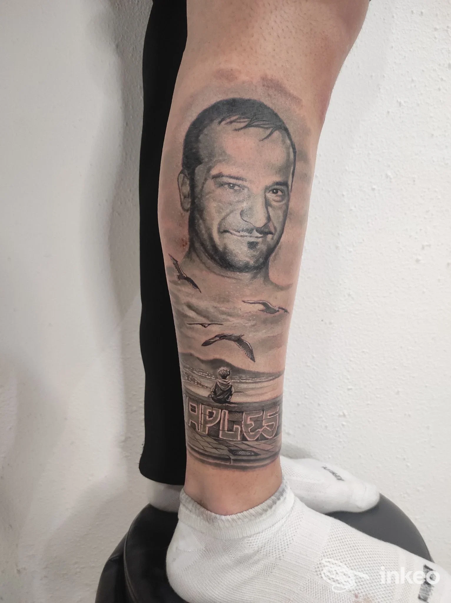 Tatuaggio realistico sul polpaccio raffigurante un volto umano e un paesaggio marino, realizzato da Thaba Tattoo a Crispano, visibile chiaramente sulla pelle.