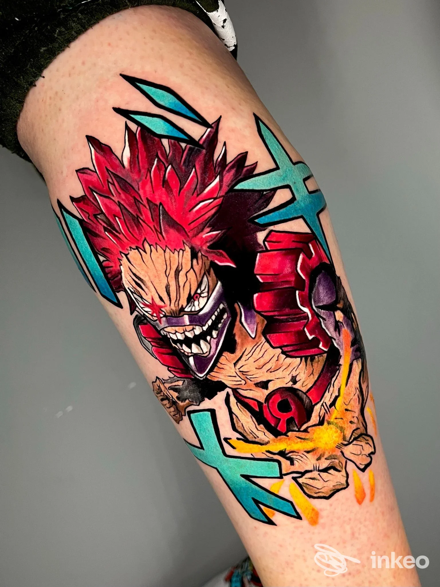 Tatuaggio su polpaccio con personaggio fantasy/colorato, profondi rossi e azzurro turchese, realizzato sulla pelle, senza elementi di interfaccia o watermark visibili; studio No Fear Tattoo Studio, Pozzuoli.