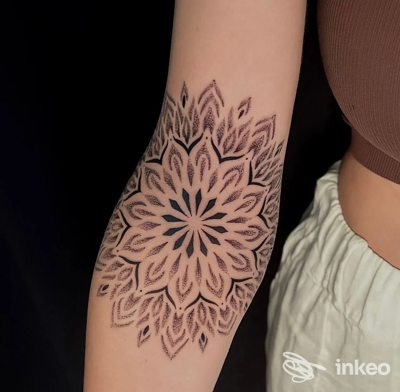 Tattoo geometrico a mandala sul braccio di una persona, tonalità nere su pelle chiara.