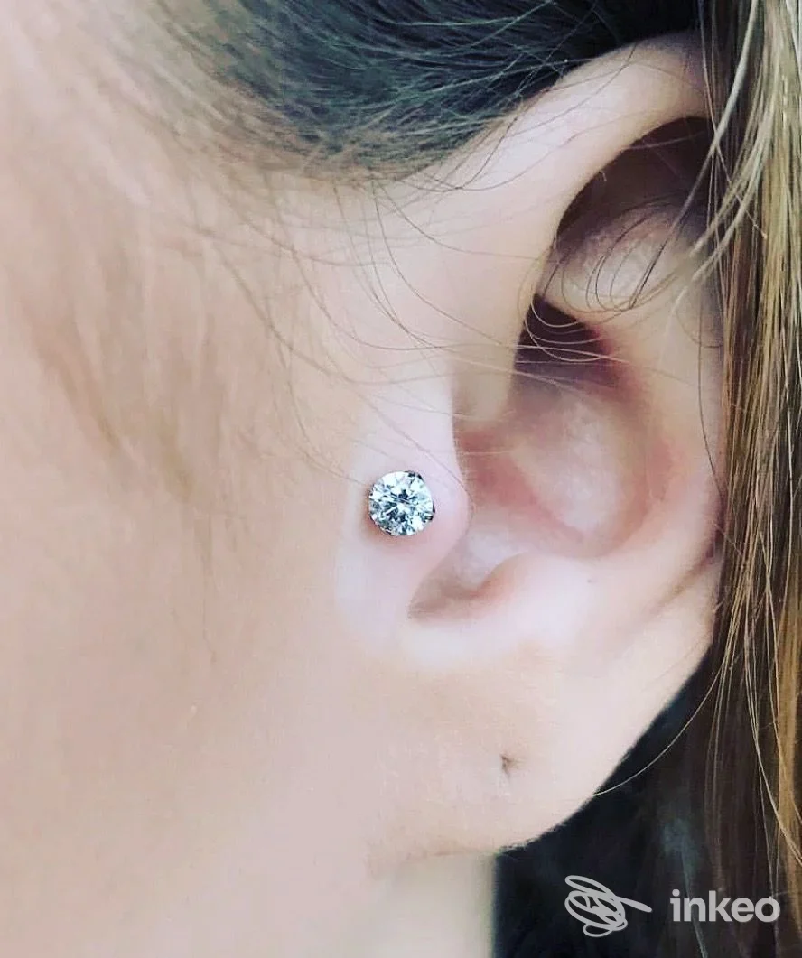Piercing all'orecchio con un brillante stud sul lobetto, scatto ravvicinato dal profilo dell'orecchio, studio Centro piercing Pippo, Melito di Napoli.