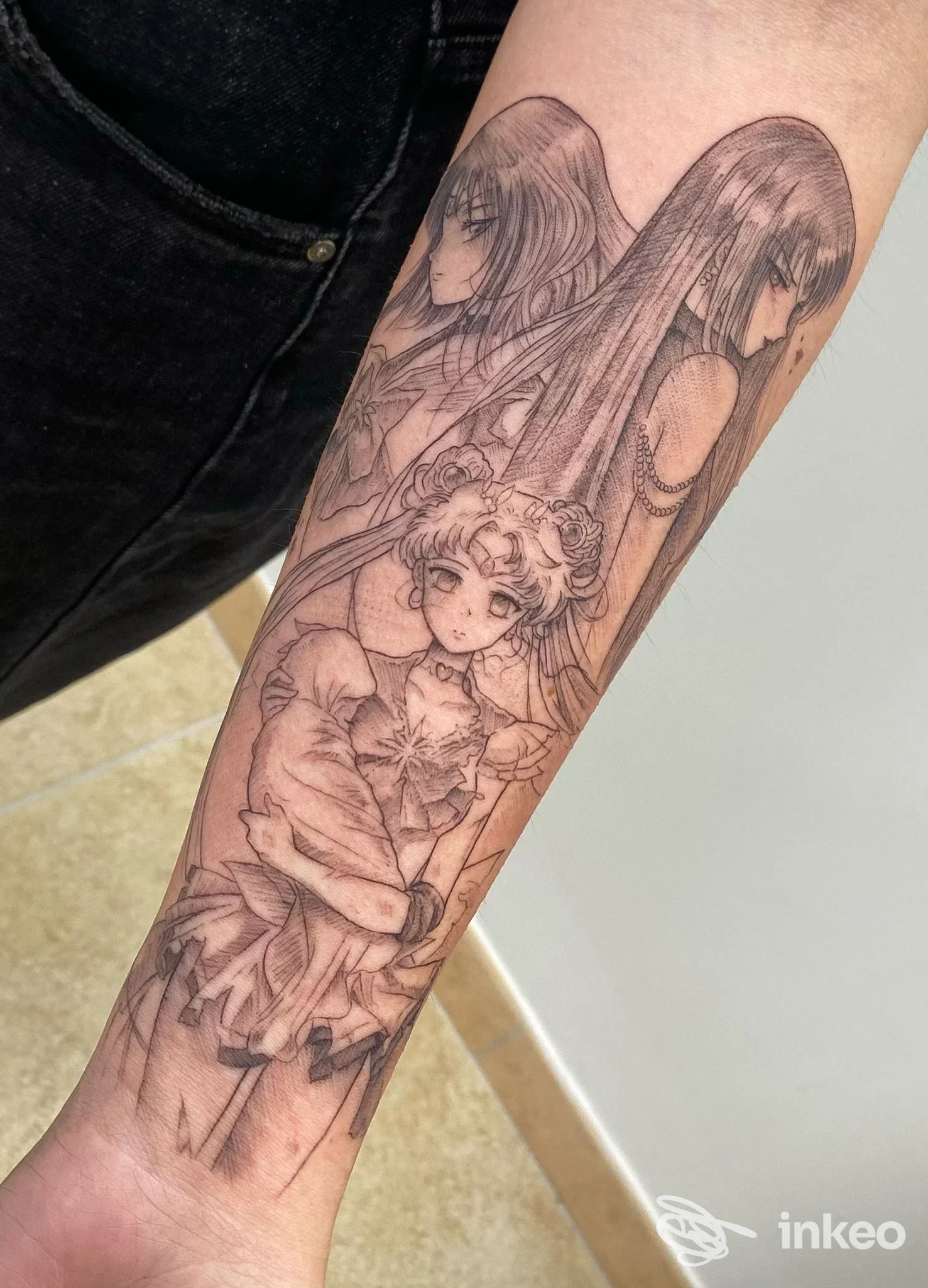 Avambraccio ritratto con tatuaggio originale raffigurante figure in stile manga, disegno lineare su pelle.