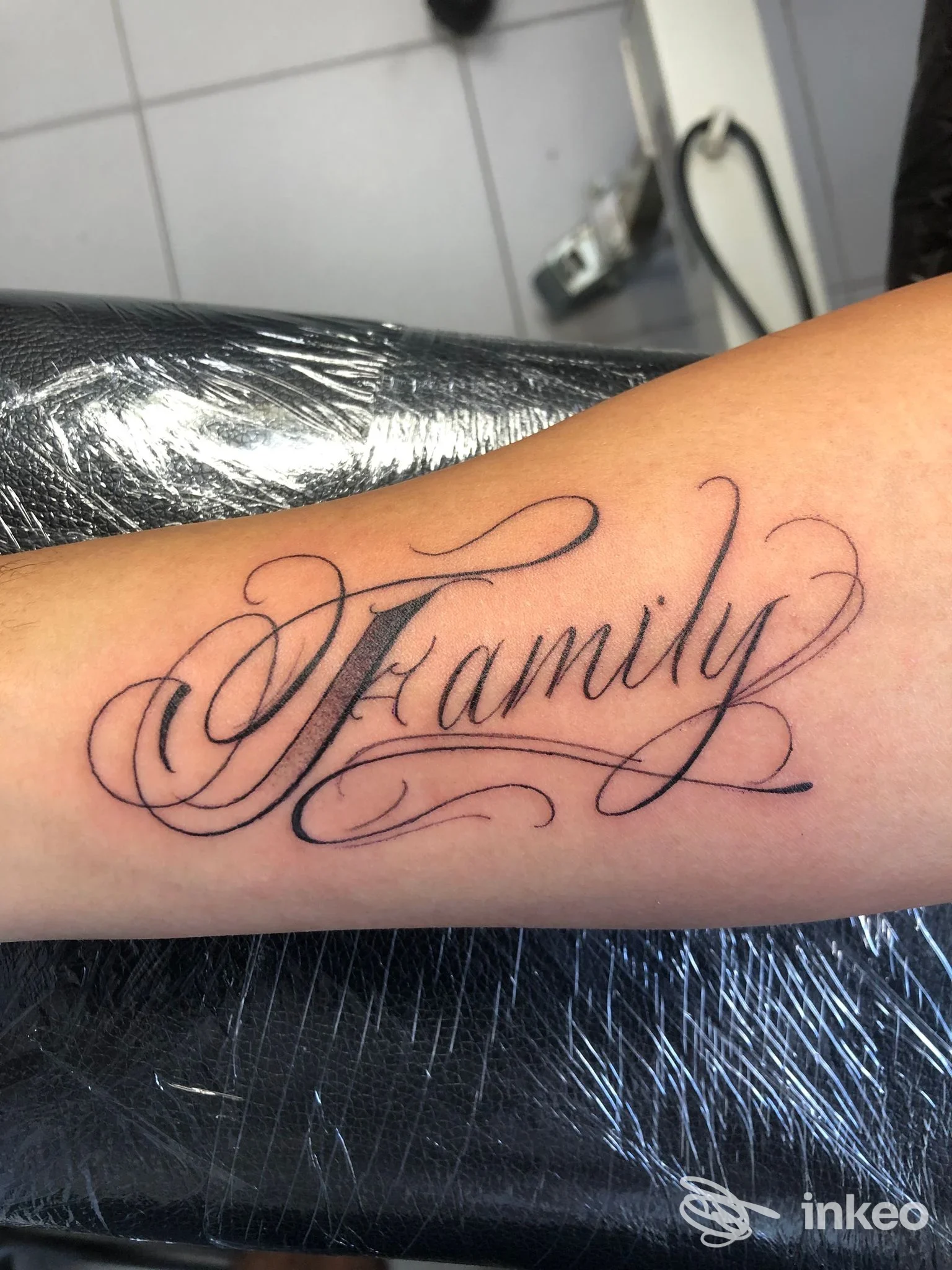 Tattoo calligrafico con la parola "Family" sull’avambraccio, realizzato da Dark Art Studio Tattoo.