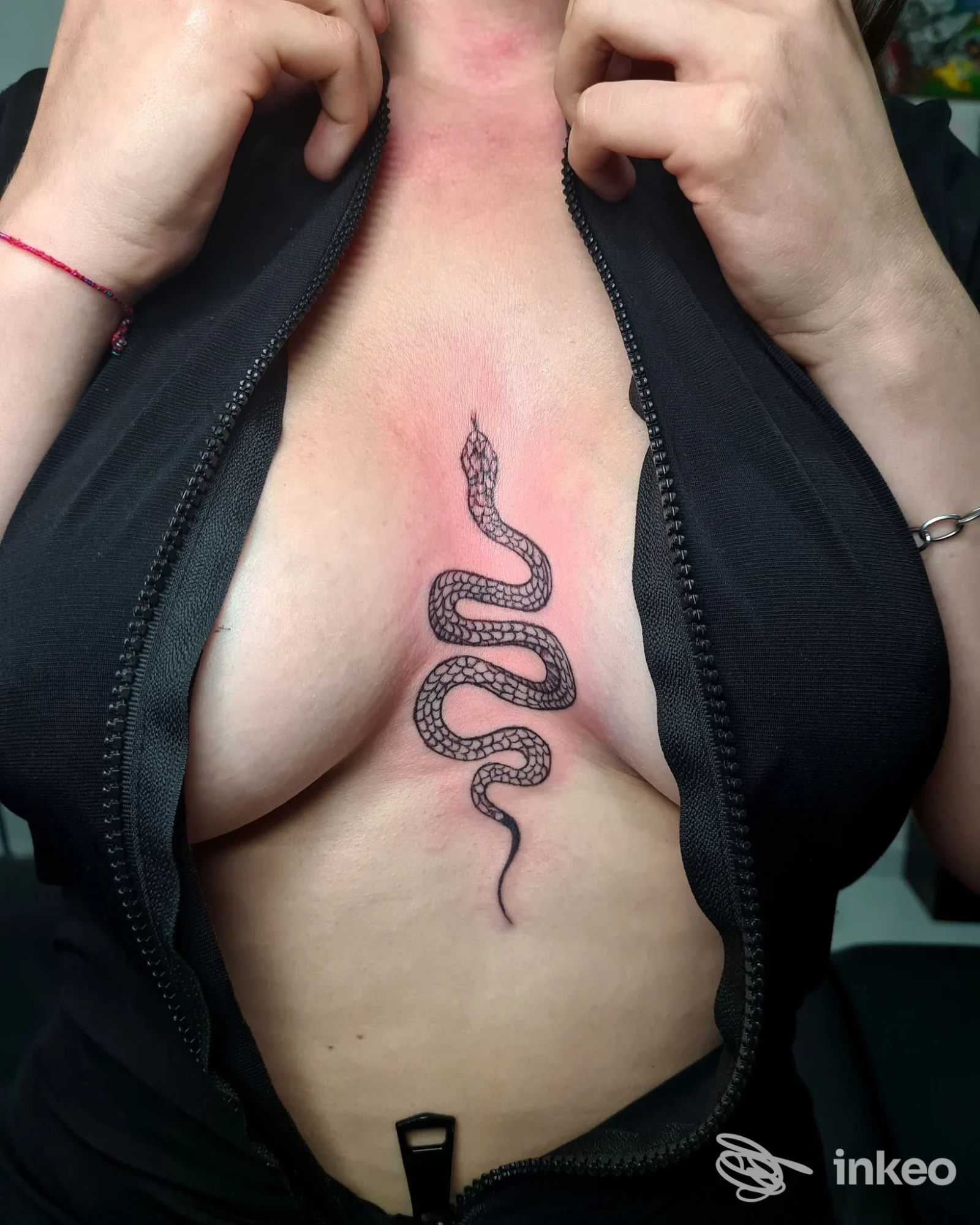 Tattoo raffigurante un serpente posizionato verticalmente al centro del torace, realizzato direttamente sulla pelle.