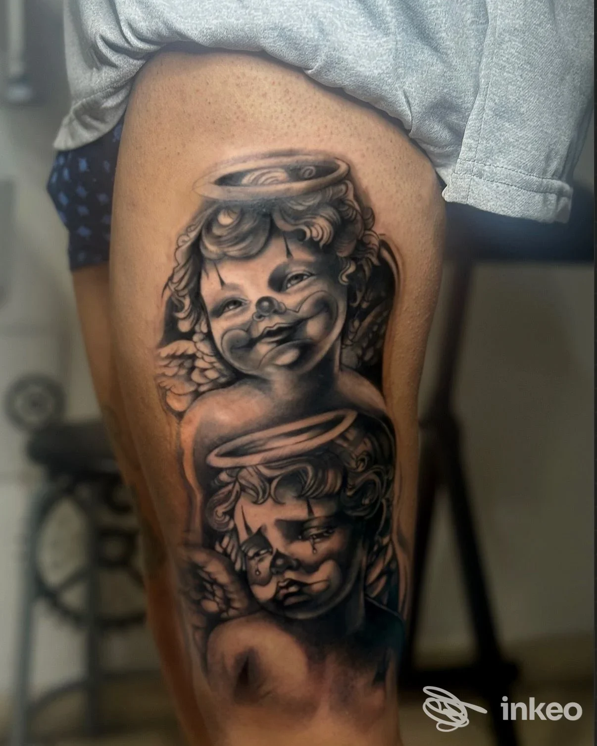 Tattoo realistico su gamba raffigurante due angeli con aureole, senza overlay sociale o contenuti non corporei.