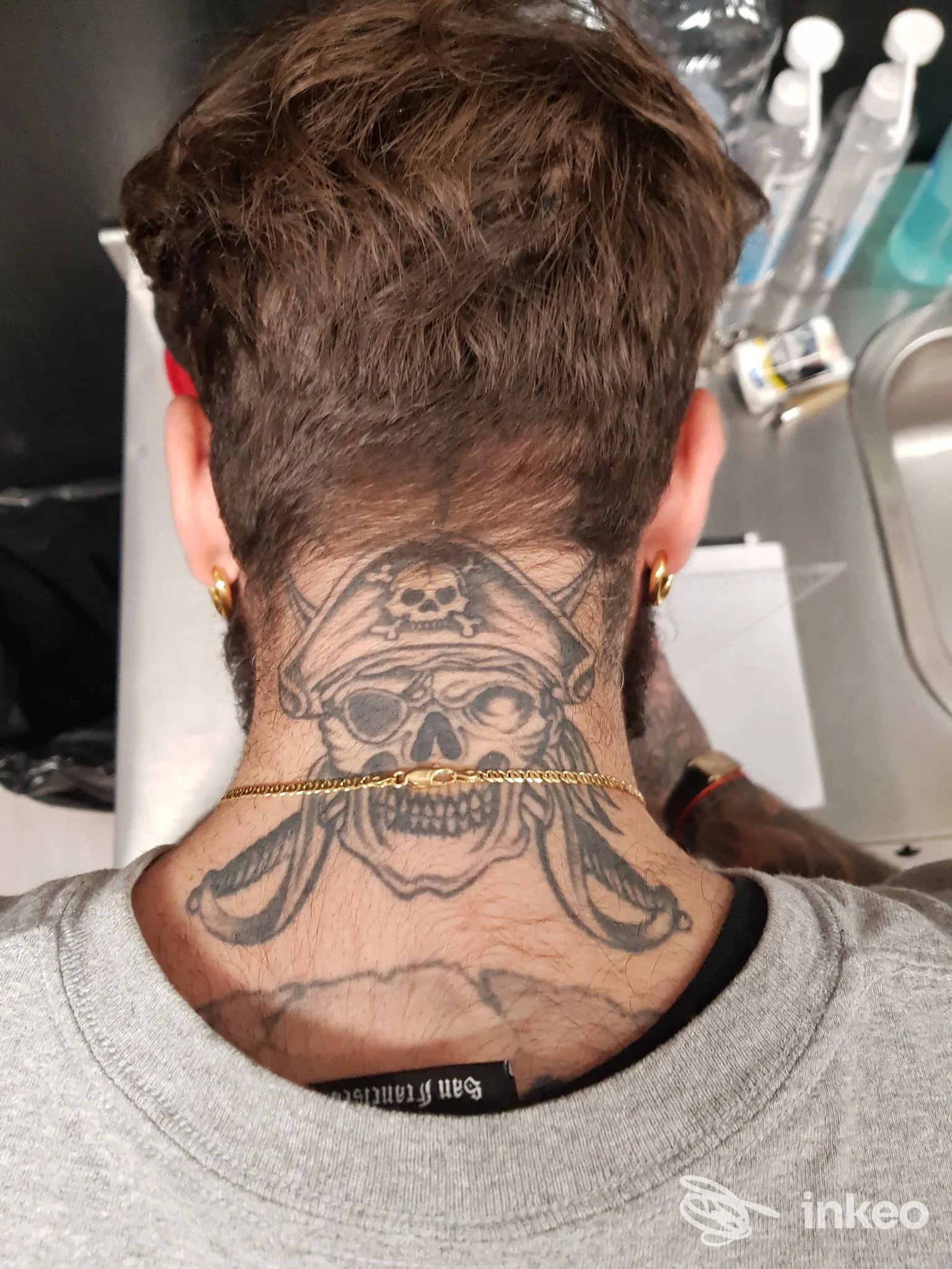Parte posteriore del collo di una persona con un tatuaggio realistico raffigurante un teschio piratesco, visibile la nuca; scatto dal retro, Napoli, studio With Love Tattoo.