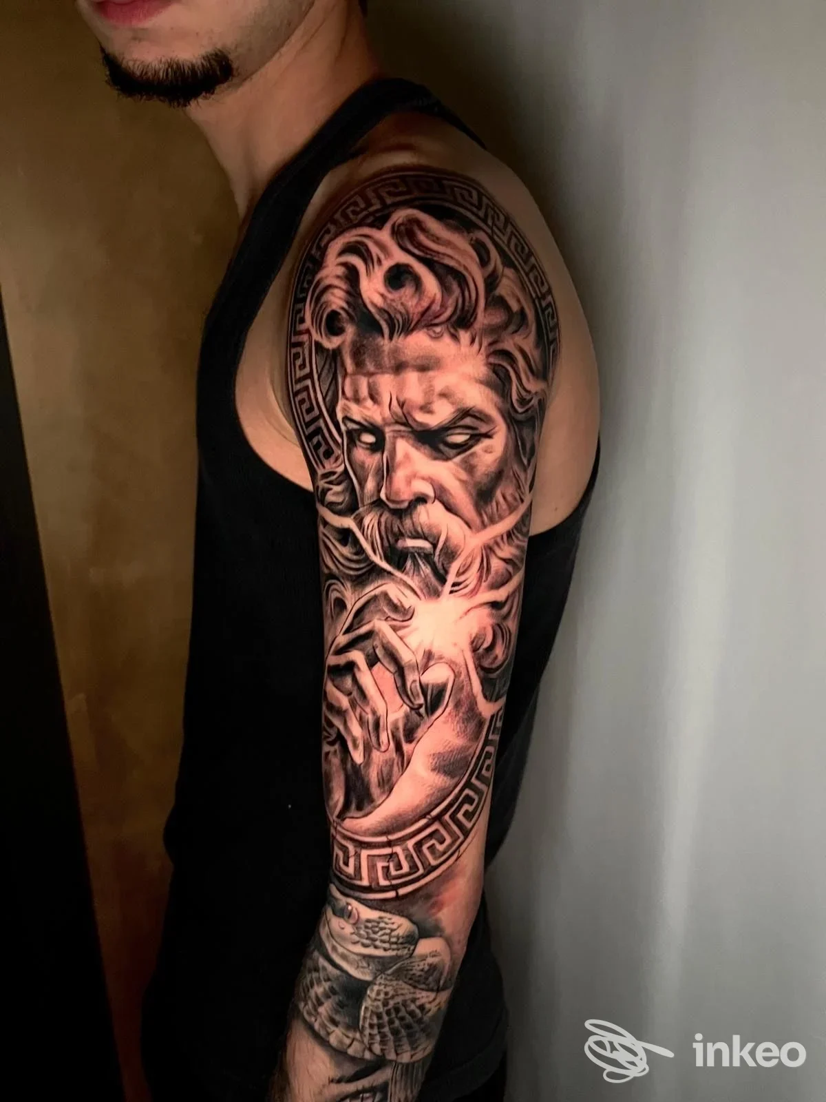 Braccio di uomo con tatuaggio realistico e scuro di grande formato, raffigurando una figura, realizzata sulla pelle, con contorni definiti e sfumature intense.