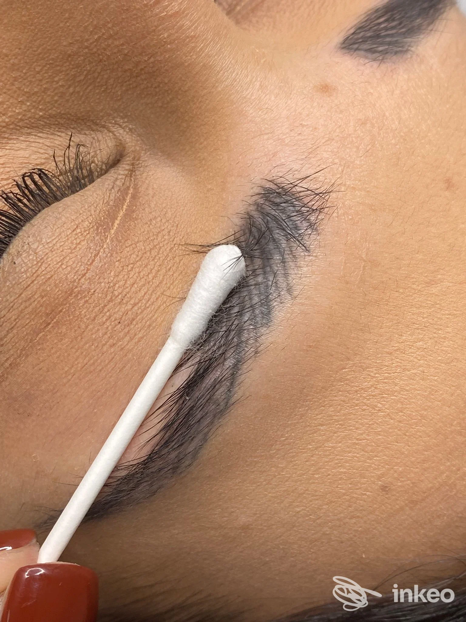 Primo piano di un trucco permanente sull’occhio in fase di applicazione, con un applicatore bianco che sfiora la linea delle ciglia, in studio a Marano di Napoli.