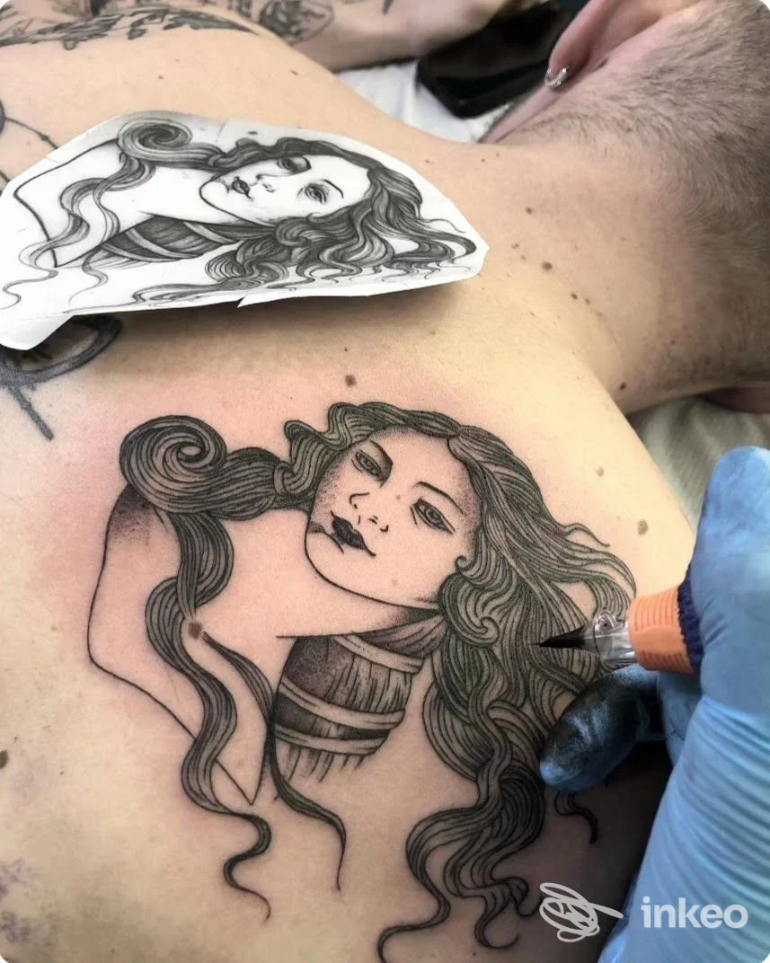 Tattoo in corso sull'avambraccio/spalla con figura femminile dallo stile linework, accompagnato da stencil su pelle reale, operatore con guanto al lavoro.