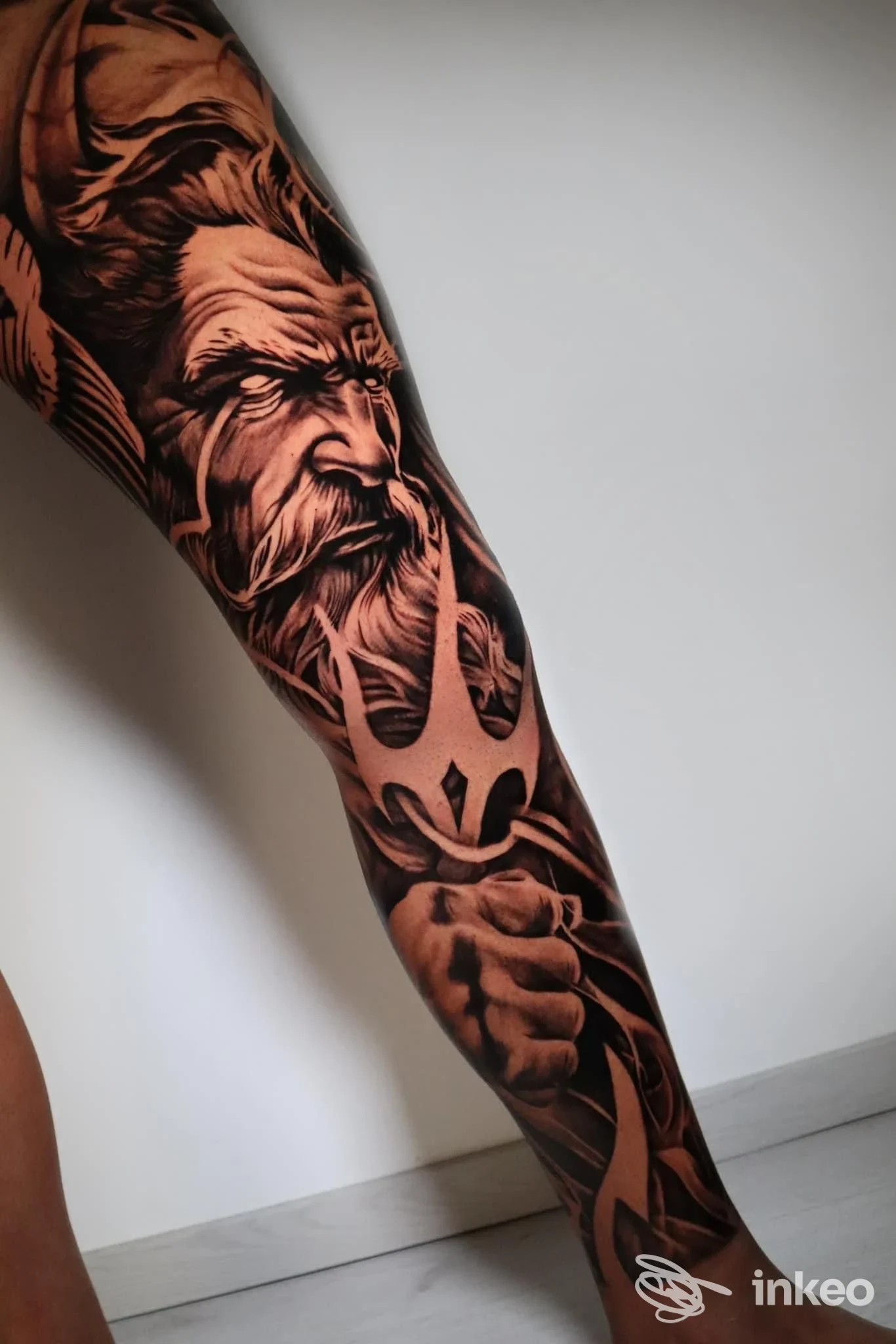 Tattoo a braccio: tatoo in stile realistico/giapponese su avambraccio sinistro, con ritratto di uomo barbuto e dettagli scuri su sfondo nero; luce neutra in primo piano.