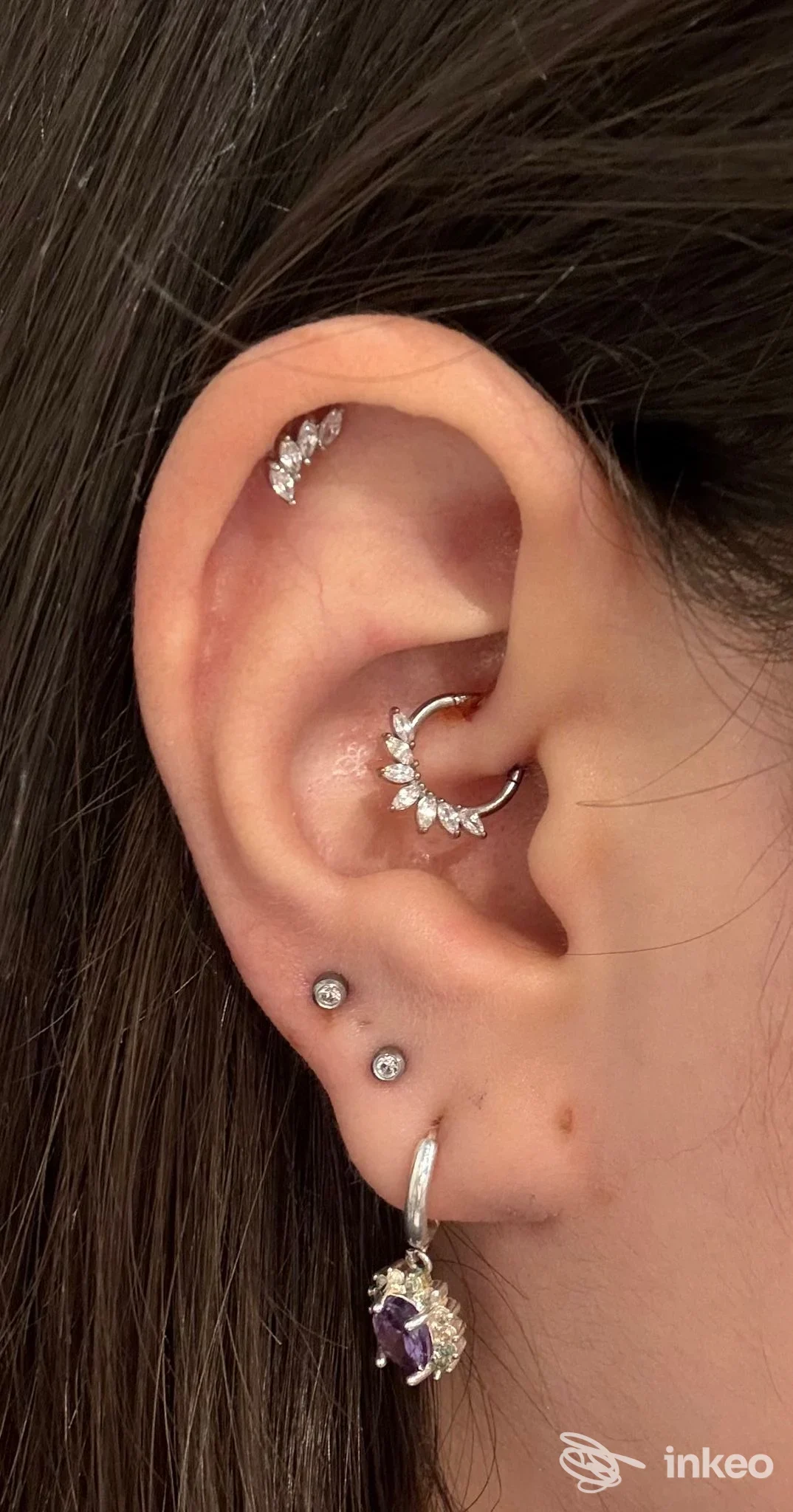 Orecchio sinistro con piercing singolo lungo lobi e gioielli in metallo bianco, presenza di più piercing sull'orecchio, studio ORING, Napoli.