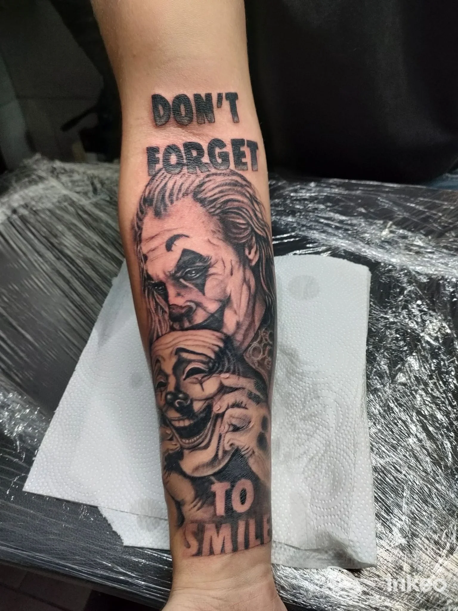 Tattoo sul braccio con testo "DON'T FORGET TO SMILE" e ritratto di una figura, realizzato su pelle da Brothers Ink Tattoo a Giugliano in Campania