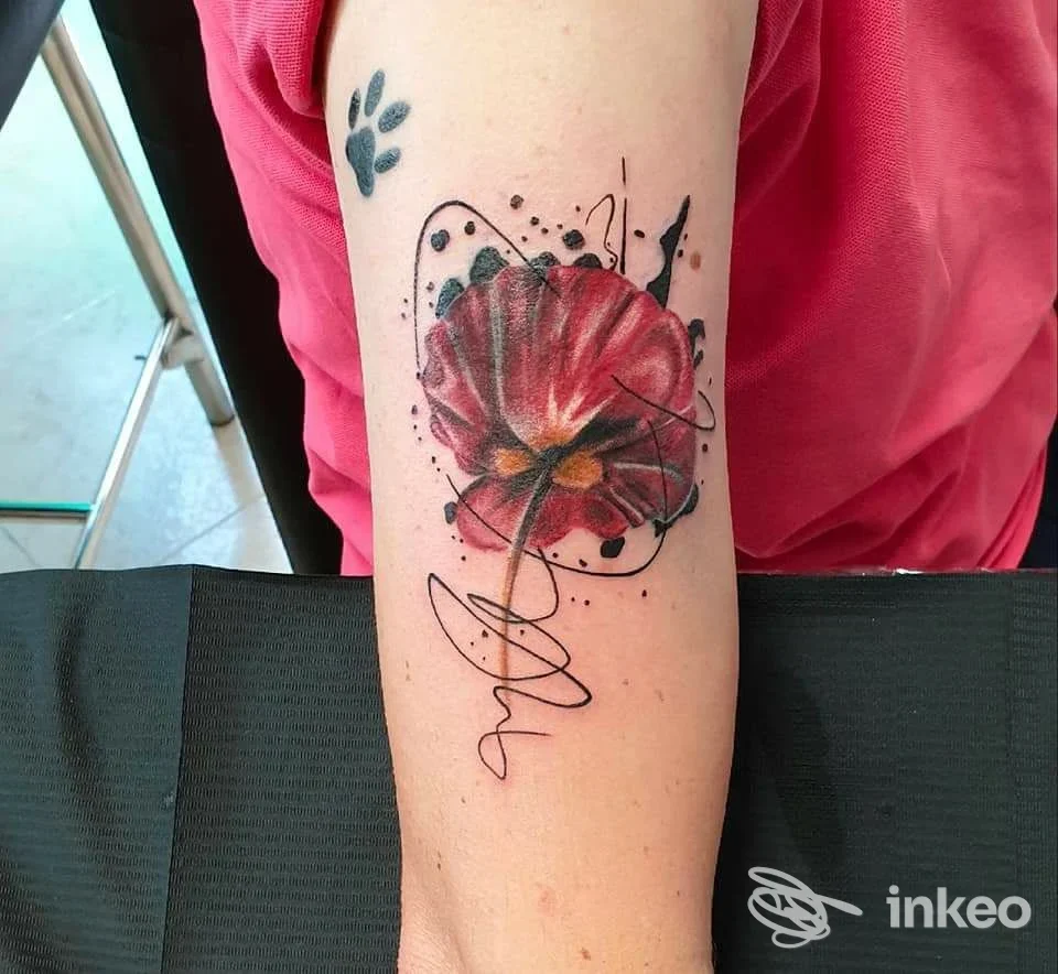 Tatuaggio realistico di un grande fiore rosso su pelle, con linee astratte intorno, situato sul braccio di una persona, realizzato dallo studio Michela Ragozzino Tattoo Studio a San Prisco.