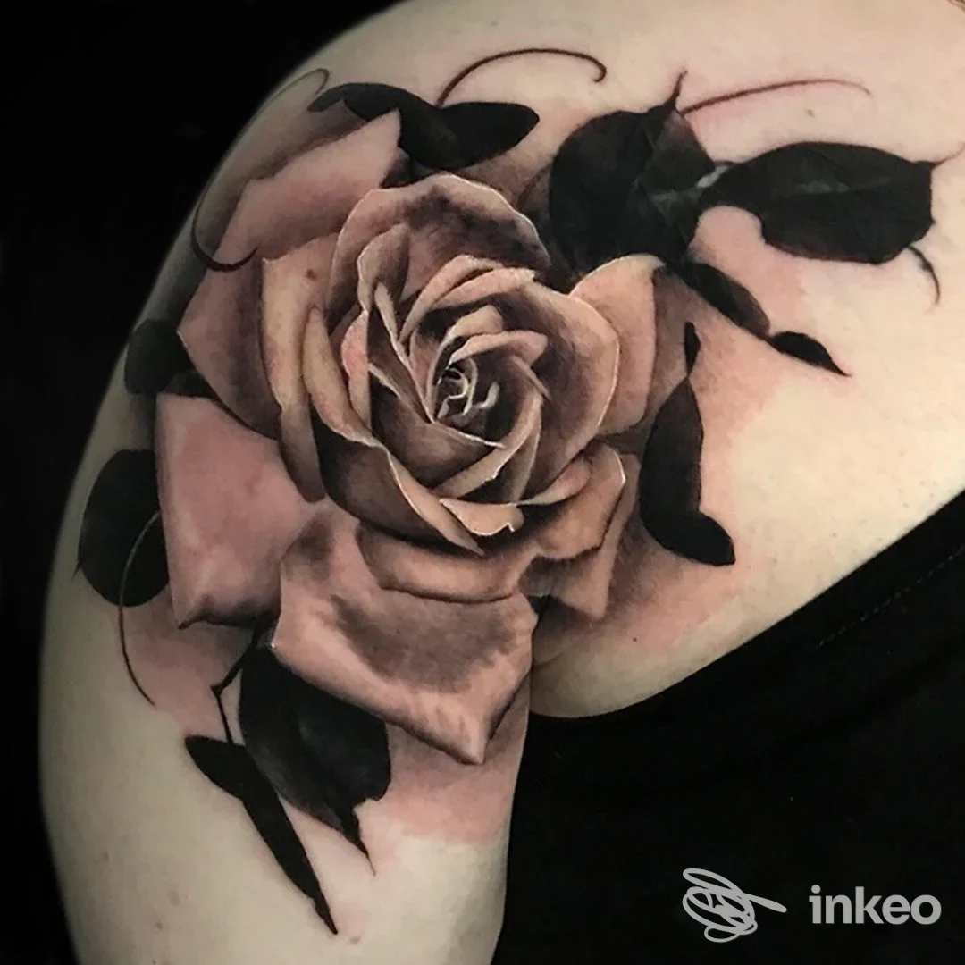 Tatuaggio realistico di rosa grigia su pelle, visibile sulla spalla/braccio, senza testo o interfacce.