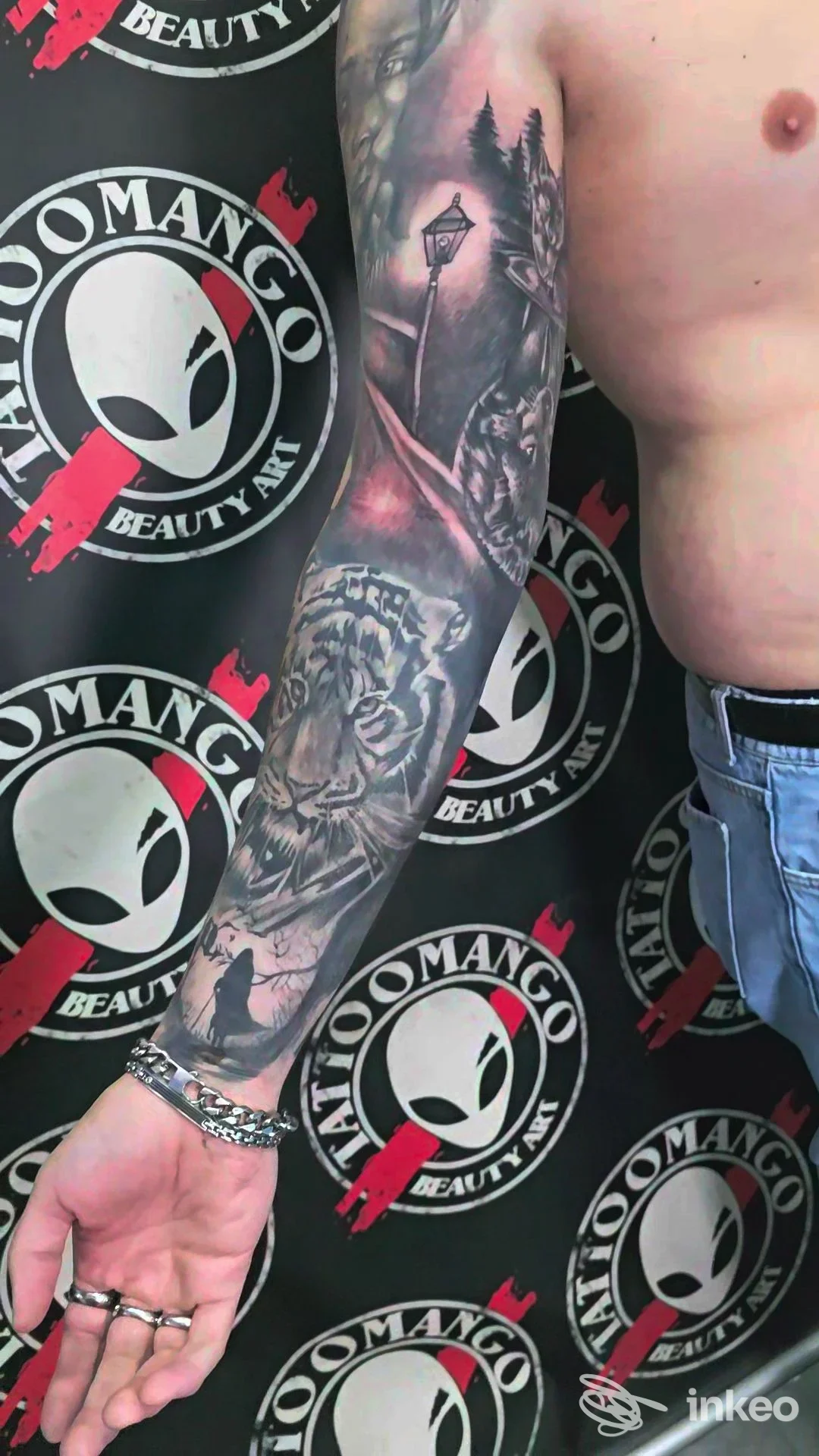 Braccio di un uomo con tatuaggio realistico su pelle: scena in tonalità grigie di paesaggio urbano e lampione, realizzato dallo studio Tattoomango a Napoli.
