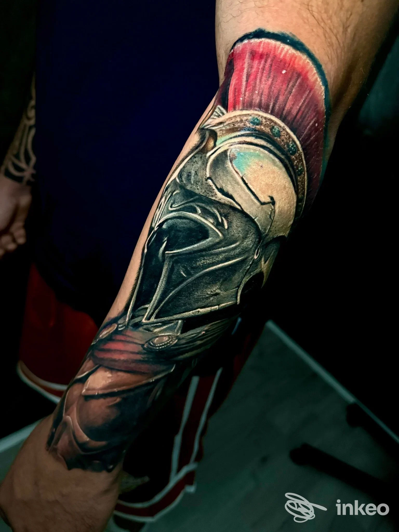 Tattoo sul braccio raffigurante un elmo metallico con piume rosse, realizzato presso Nexus Tattoo Studio a Pignataro Maggiore.