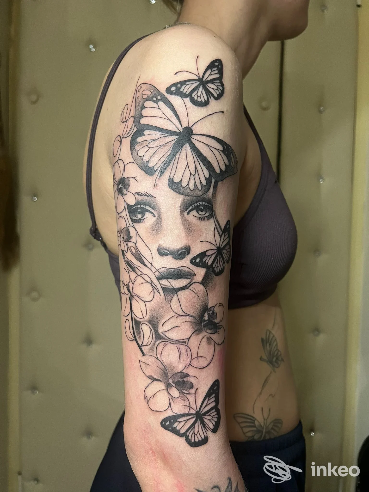 Tattoo sul braccio sinistro di una donna con farfalle e fiori, realizzato sulla pelle, senza sovrimpressioni di piattaforme social o contenuti non corporei.