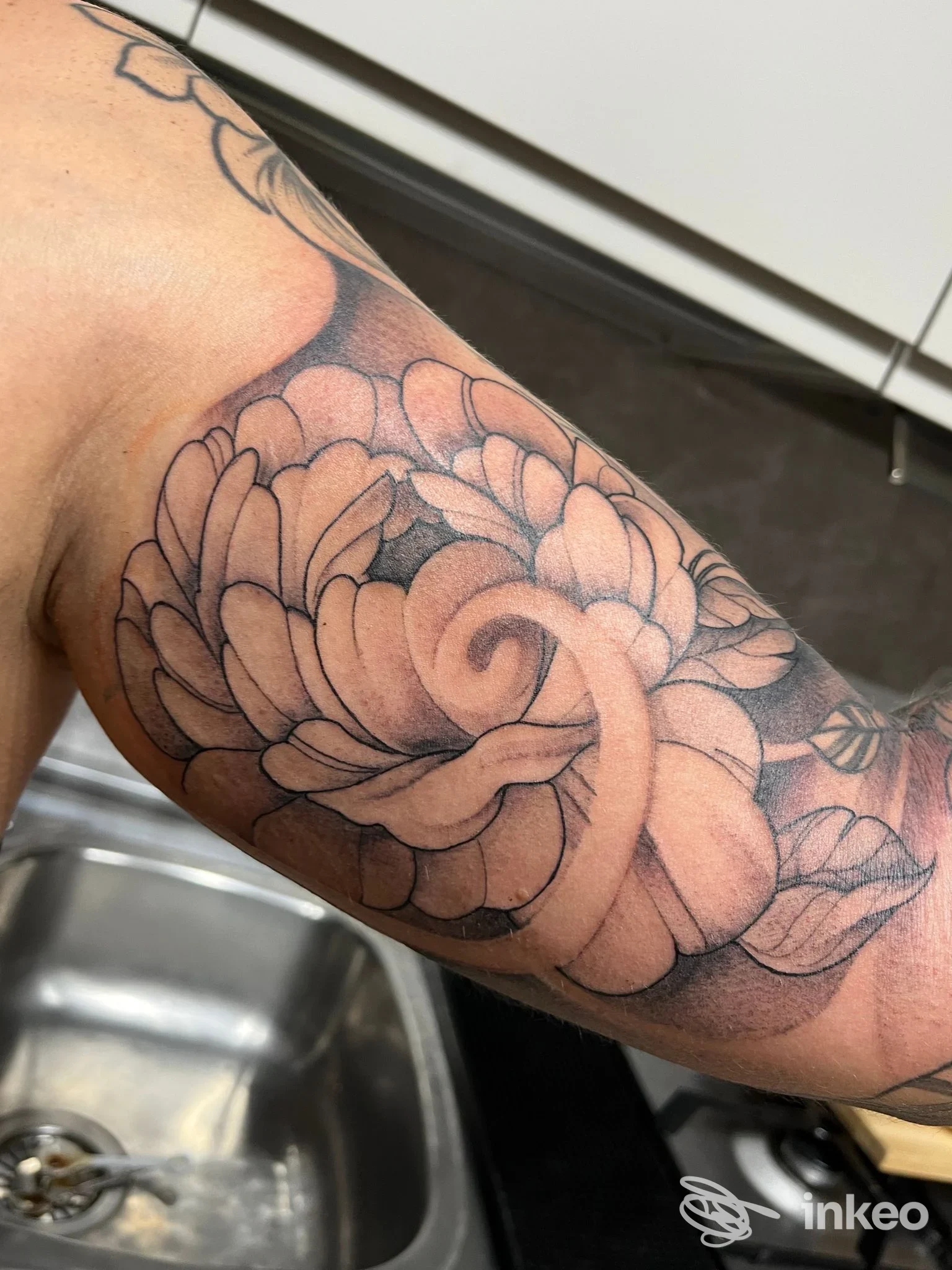 Braccio con tatuaggio floreale ben definito visibile in primo piano, scatto in cucina nello studio Officina Artistica, Napoli.