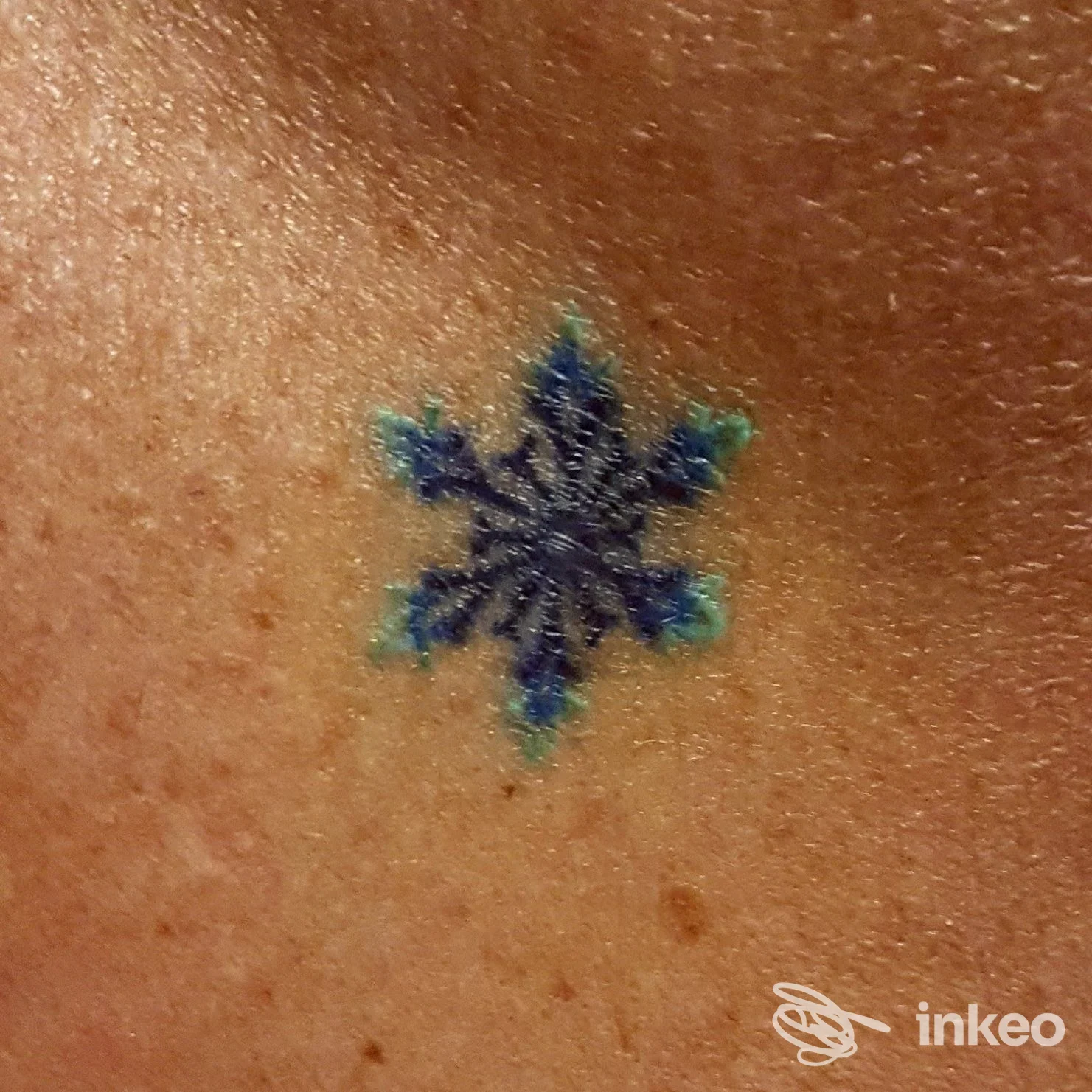 Tatuaggio piccolo a fiocco di neve blu sulla pelle, realizzato presso TipInk Tattoo Studio, Nocera Inferiore.