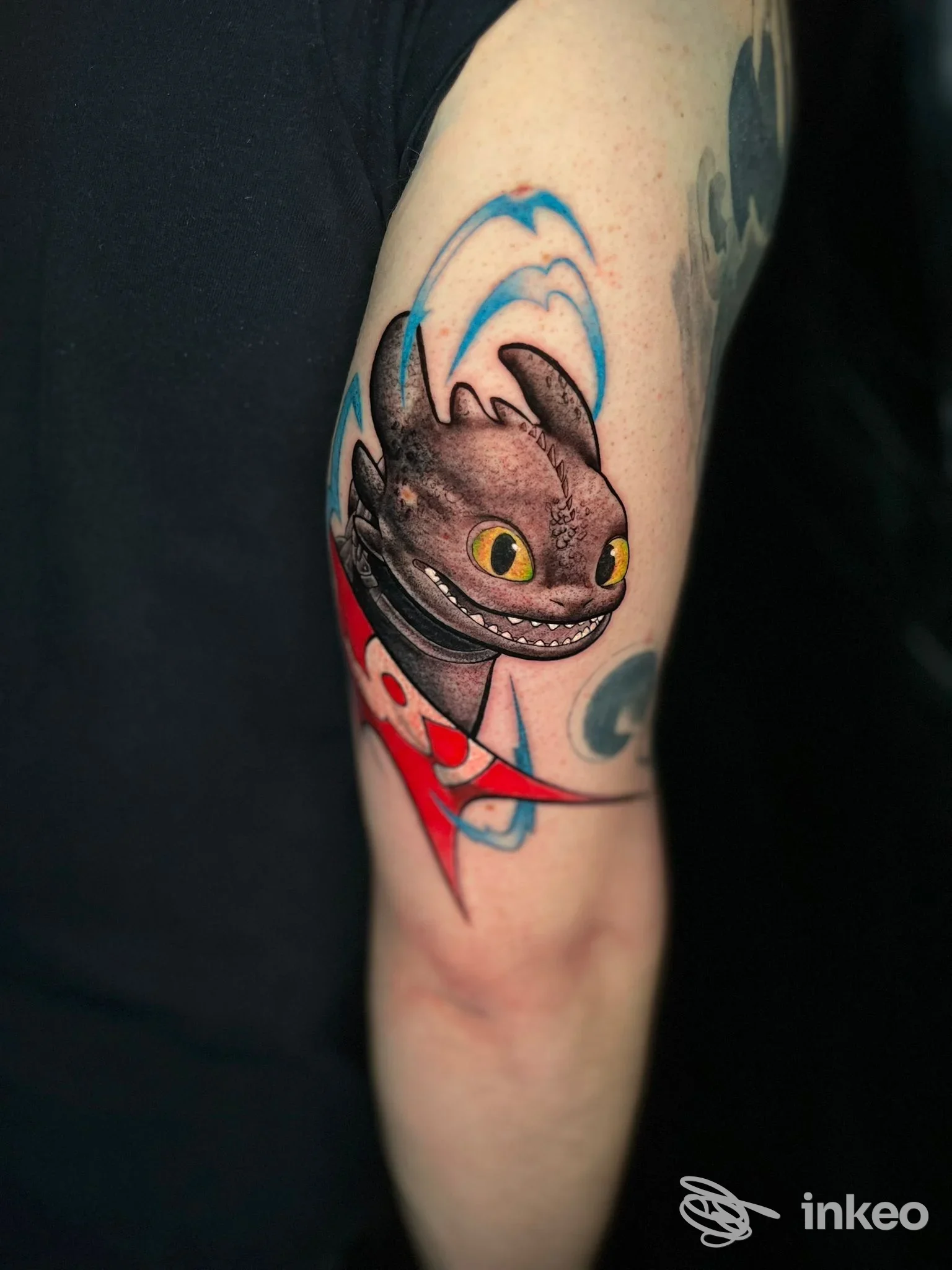 Tattoo colorato su braccio raffigurante una creatura stilizzata, contorni neri e occhi gialli, eseguito da Dark Whisper Tattoo Company.