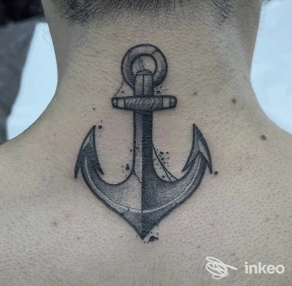 Tattoo ad ancora sulla nuca visibile sul collo, eseguito in tonalità nere e grigie, stile linework, realizzato su pelle. Studio Black Roses Tattoo 2.0, San Clemente.