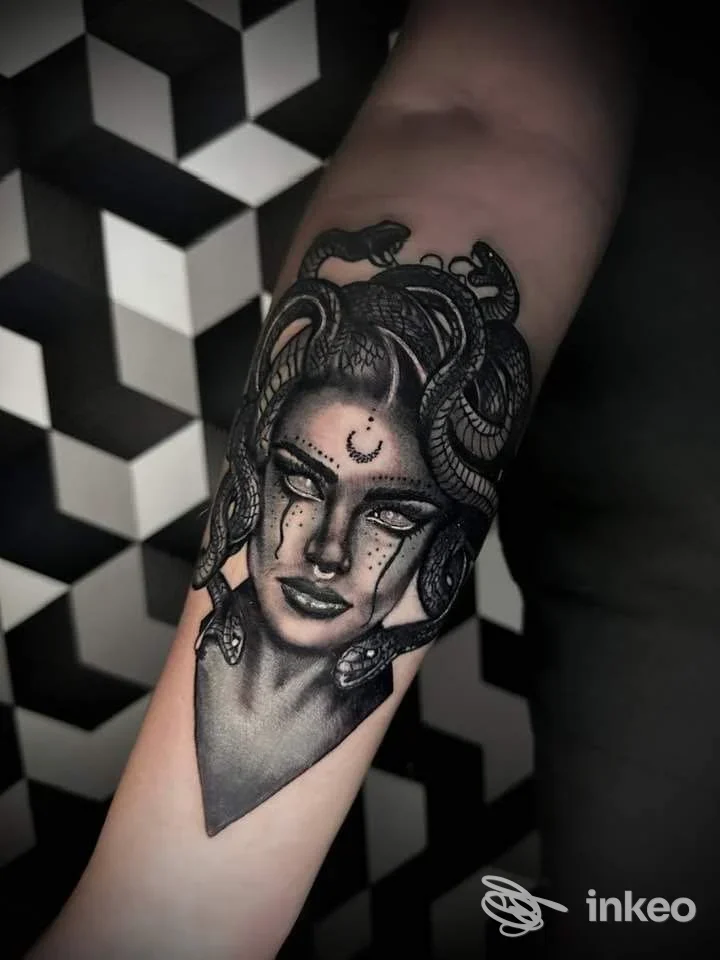 Tattoo visibile sull’avambraccio raffigurante una figura femminile con serpenti tra i capelli; lavorazione in bianco e nero con dettagli e shading, senza elementi di social media o schermo.