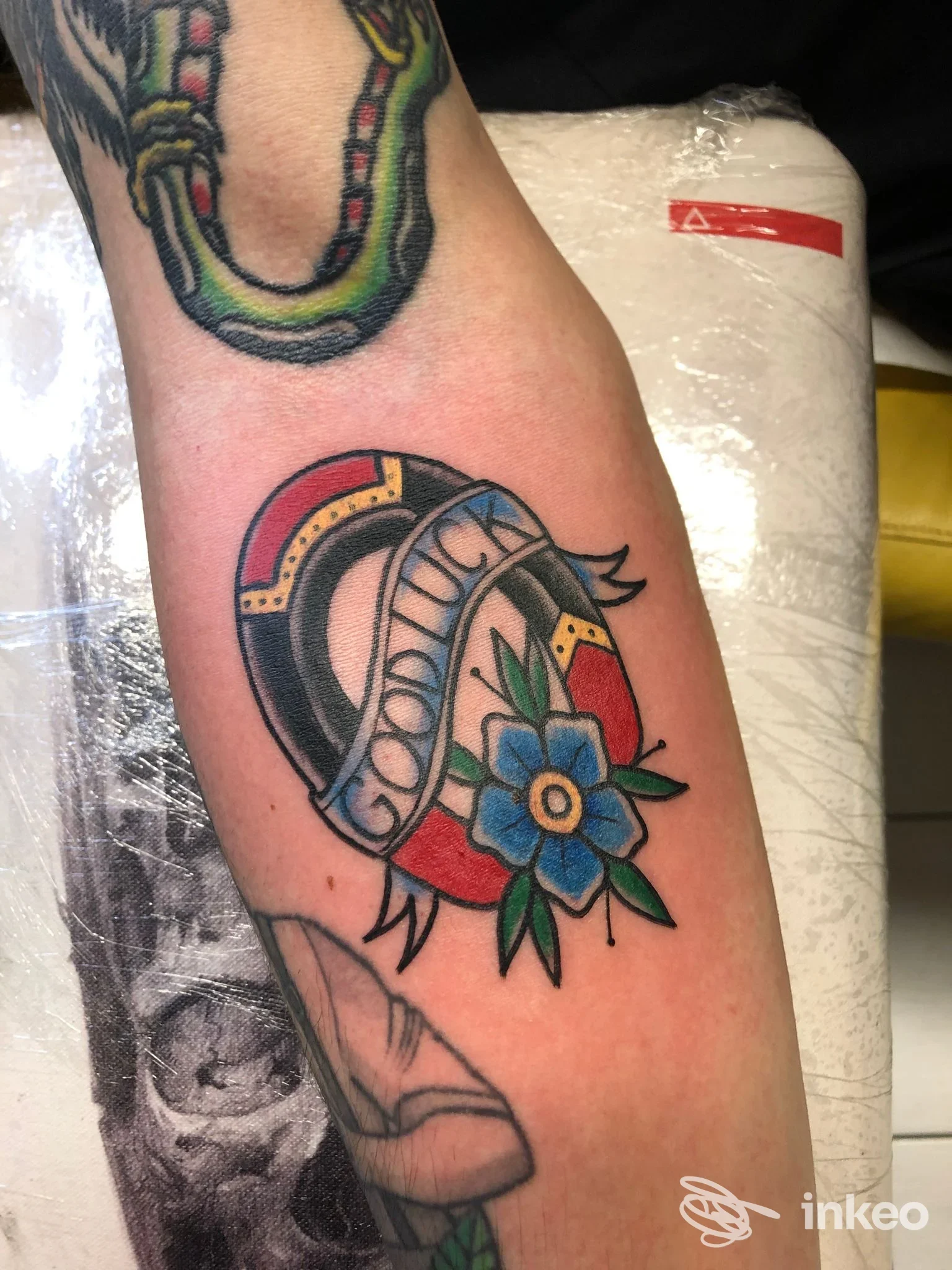 Tattoo visibile sul braccio con motivo circolare e fiore azzurro, colori vividi e linee nette; si intravede parzialmente un altro tatuaggio in alto. Studio Trentacinque, Nocera Inferiore.