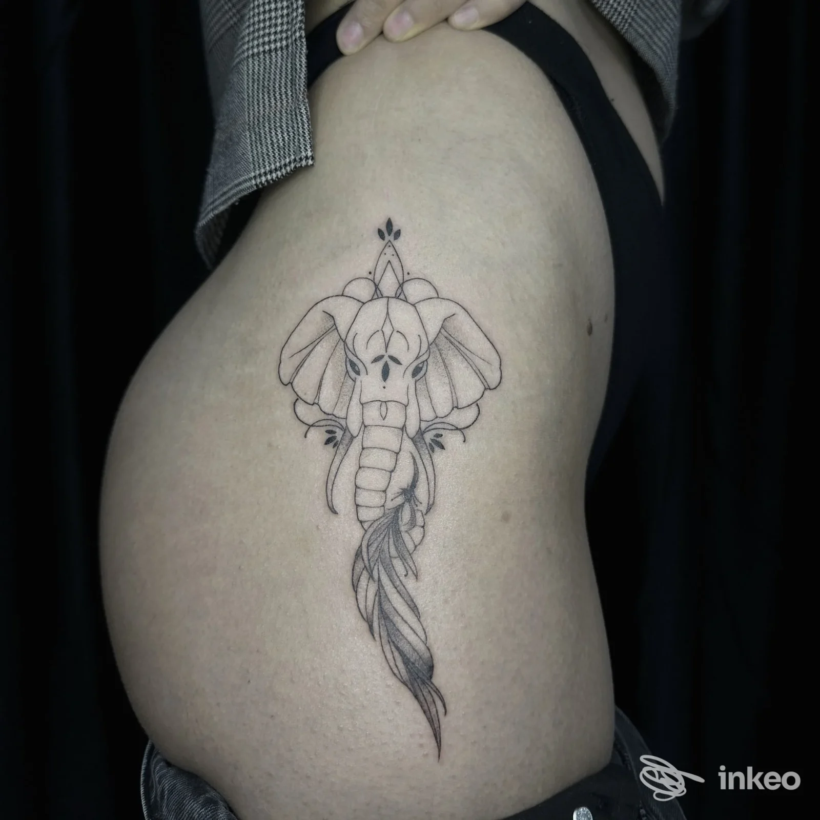 Tatuaggio corporeo sull'avambraccio raffigurante una testa d'elefante stilizzata con ornamenti geometrici e una lunga coda di piume, realizzato da Heartless Tattoo a Maddaloni.