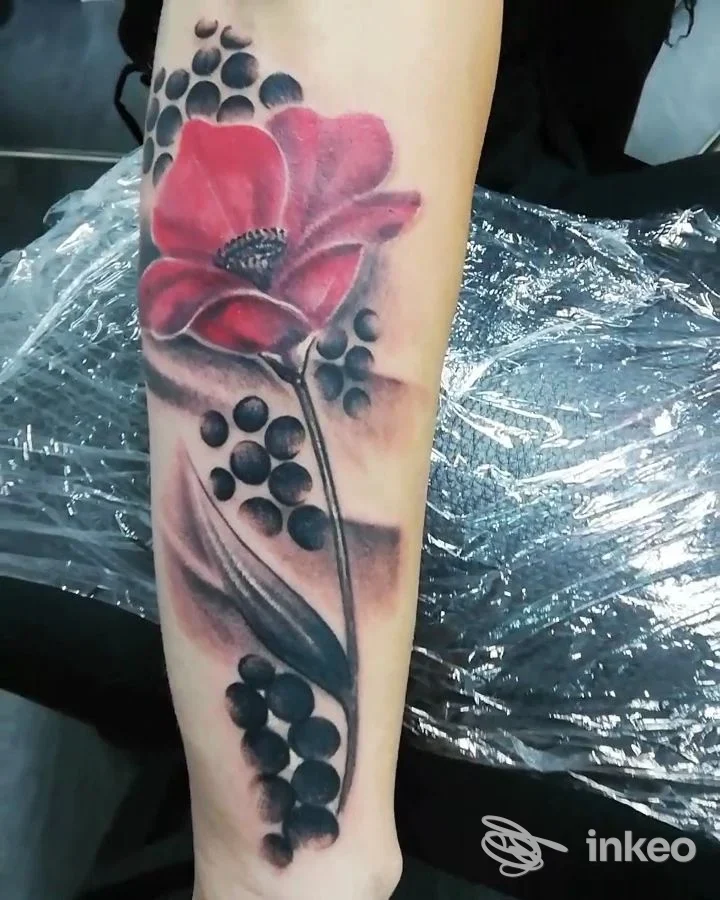 Tattoo realistico su polso: grande fiore rosso con sfumature e bacche nere lungo lo stelo, colori vividi su pelle chiara, sfondo con plastica protettiva. Studio Jo' Art Tattoo, Solofra