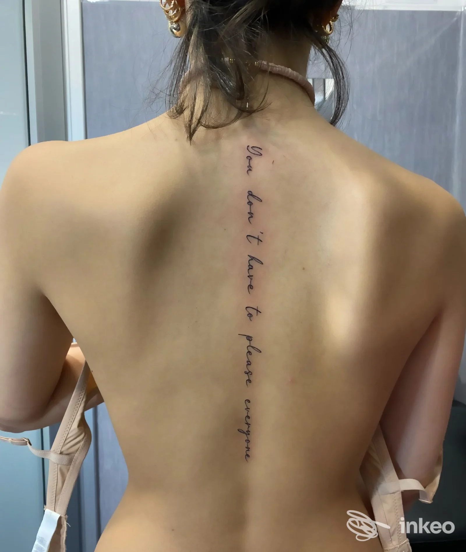Tatuaggio verticale lungo la colonna vertebrale su schiena nuda, scritto in corsivo, visibile senza mostrare il volto. Studio: Studio1 Tattoo, San Gennaro Vesuviano.