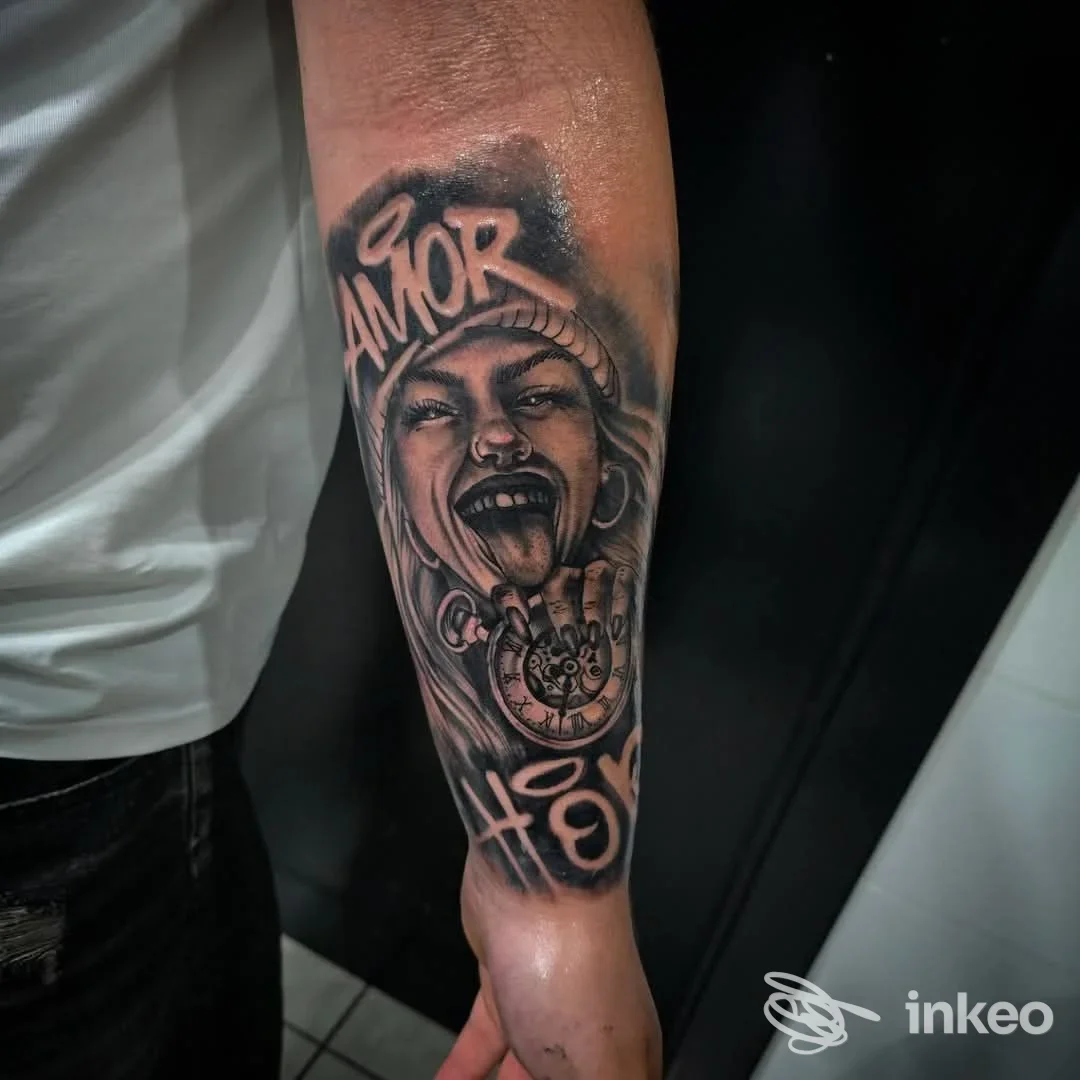 Tattoo in bianco e nero sull’avambraccio raffigurante una testa con la bocca aperta e la lingua fuori, con la parola Amor in alto: realizzato da Kairos Ink Tattoo a Scafati.