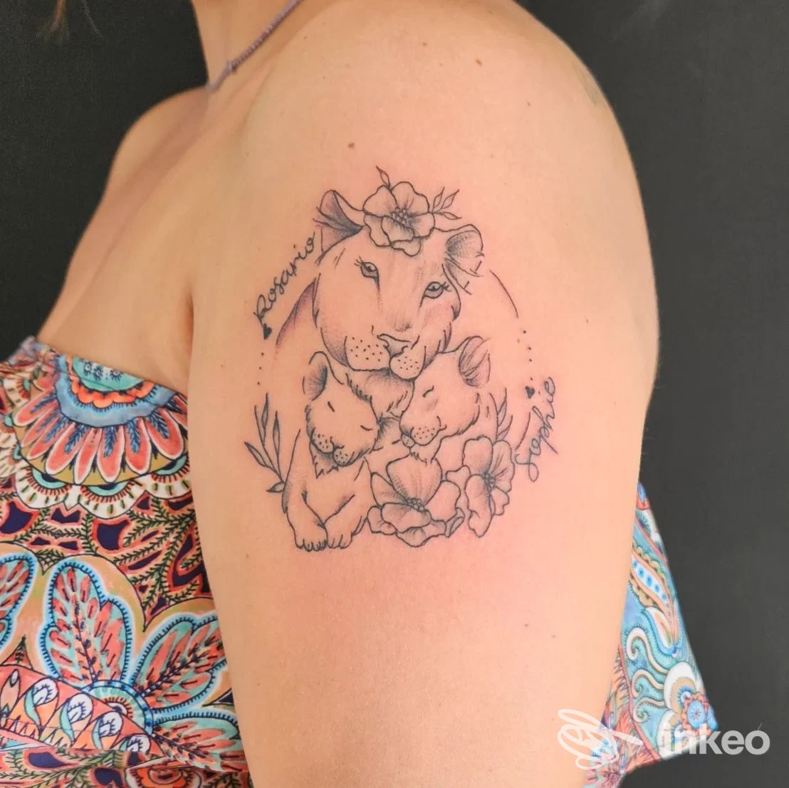 Tatuaggio lineare su braccio raffigurante una coppia di leoni e fiori, realizzato sulla pelle di una persona, senza elementi visivi di volto.